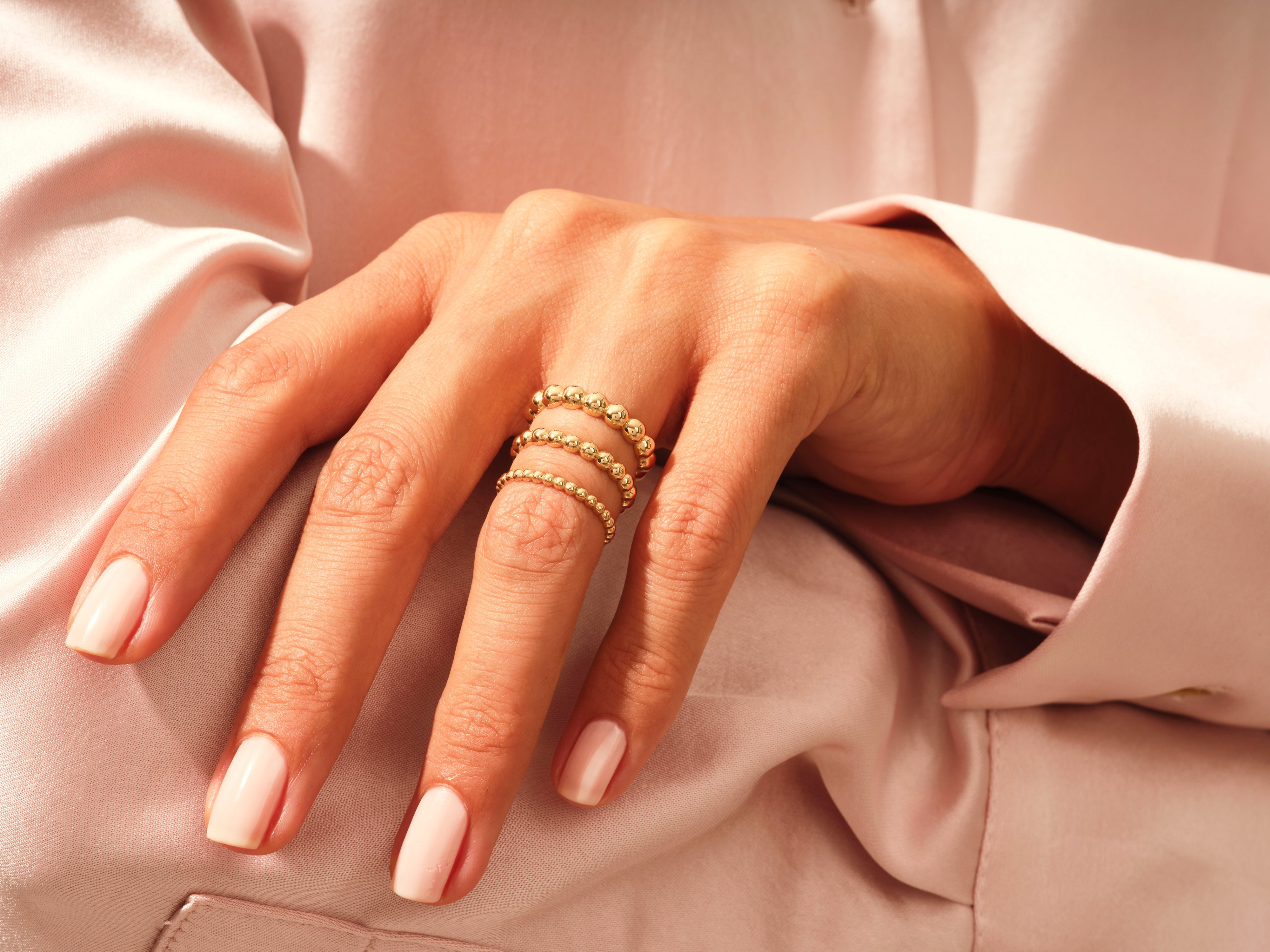 Gold beaded stacking rings on a hand, jewelry