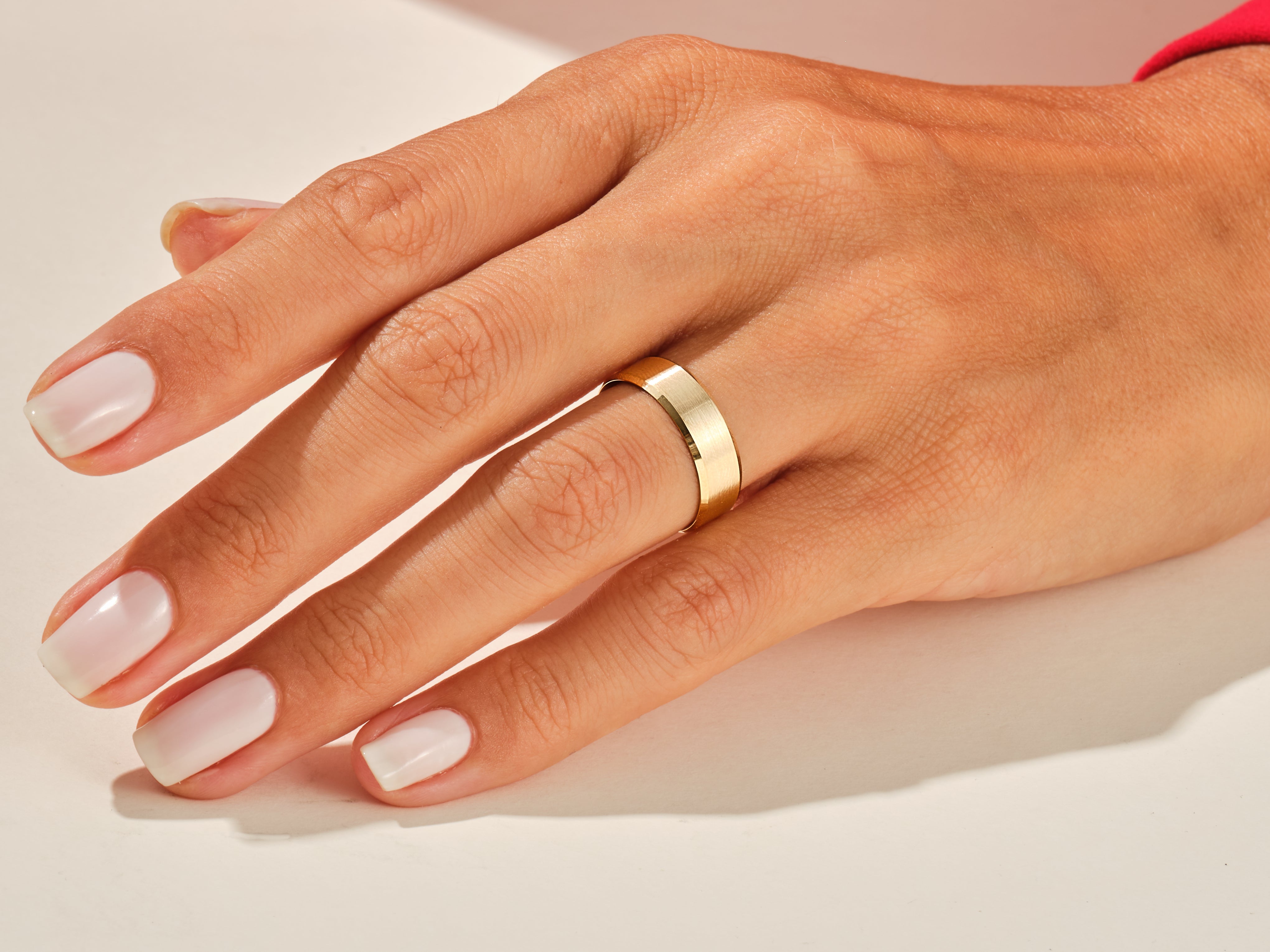 Gold band ring on a hand with manicured nails