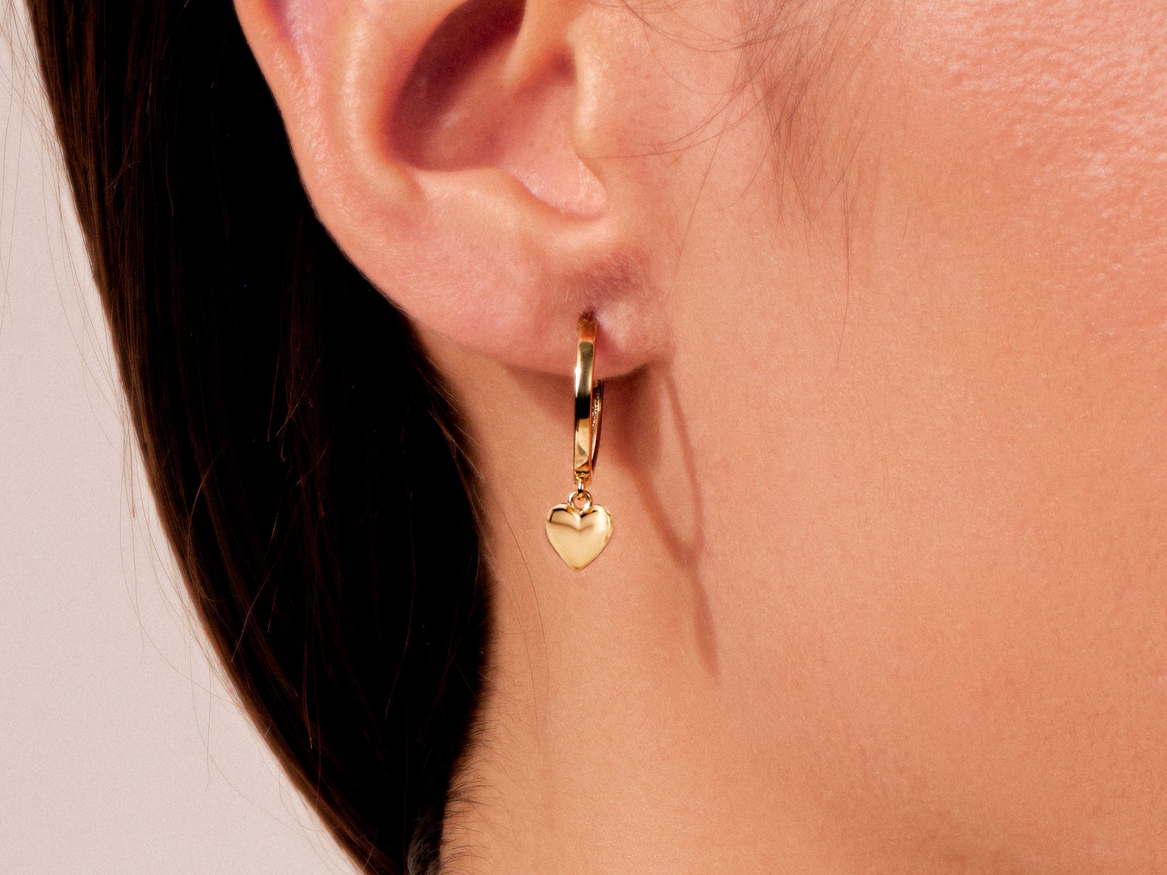 Gold hoop earring with a dangling heart charm, jewelry