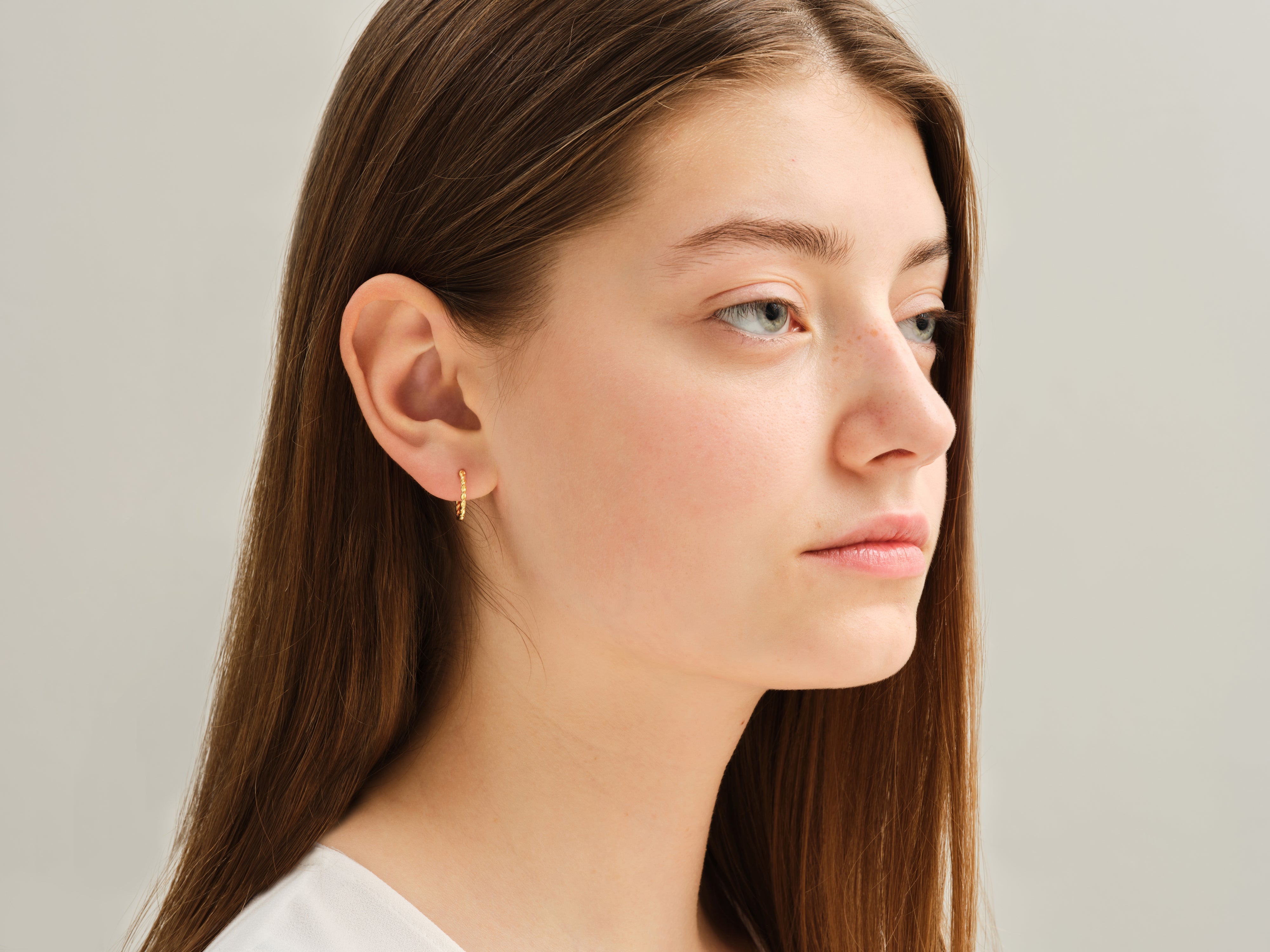 Model wearing delicate gold hoop earring from jewelry collection