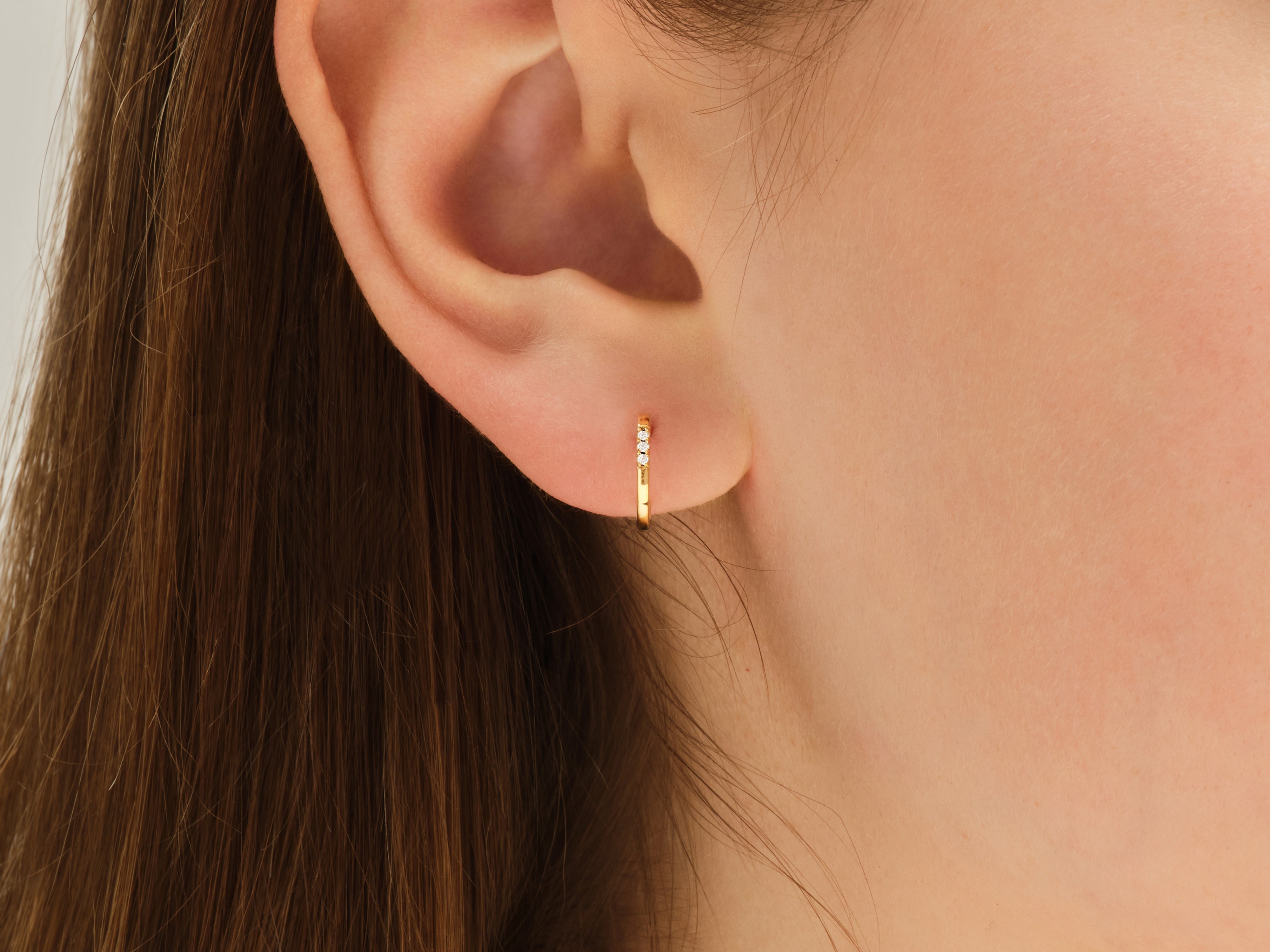 Gold hoop earring with diamonds on a woman's ear