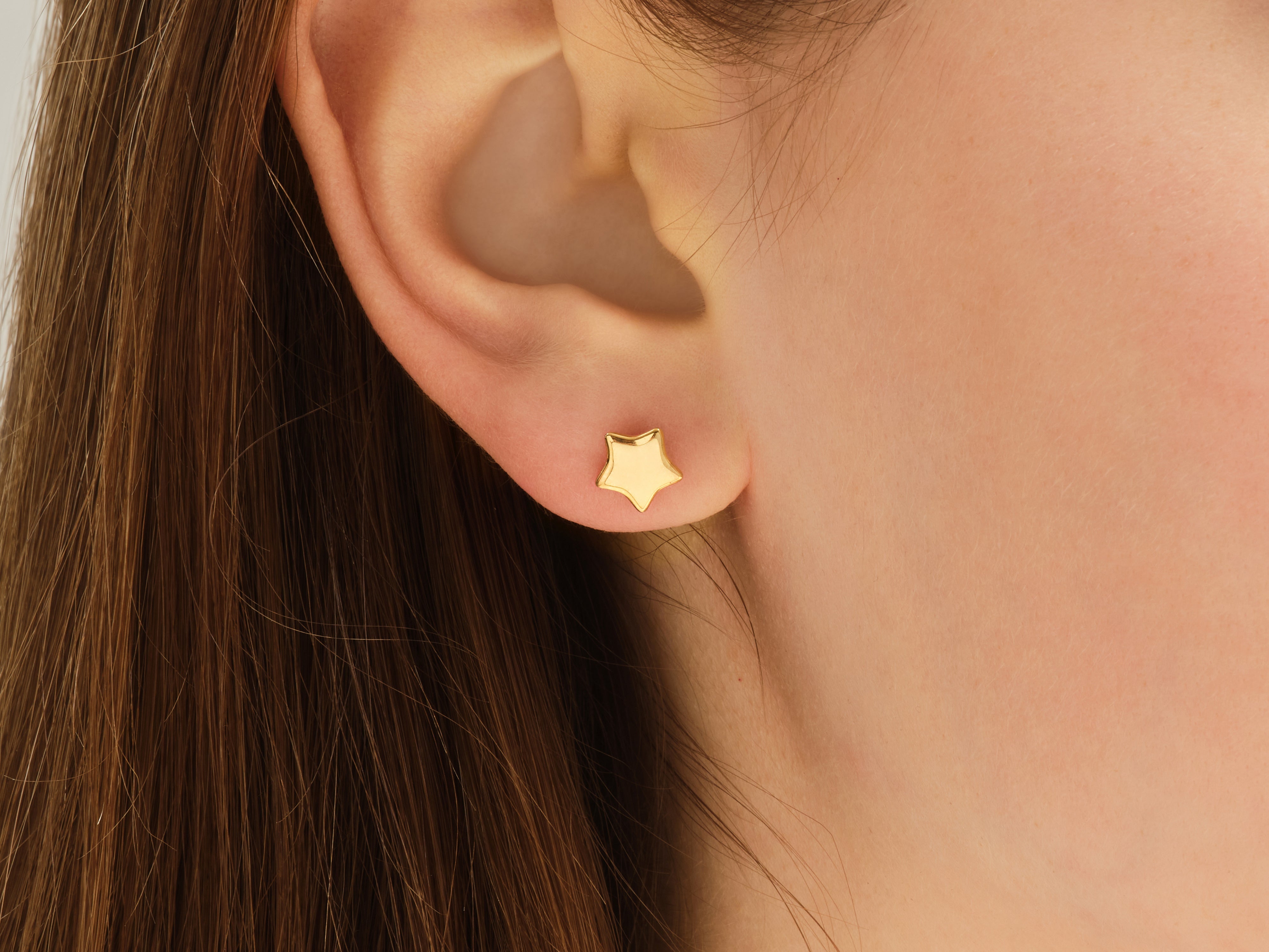 Gold star stud earring on ear, jewelry for women