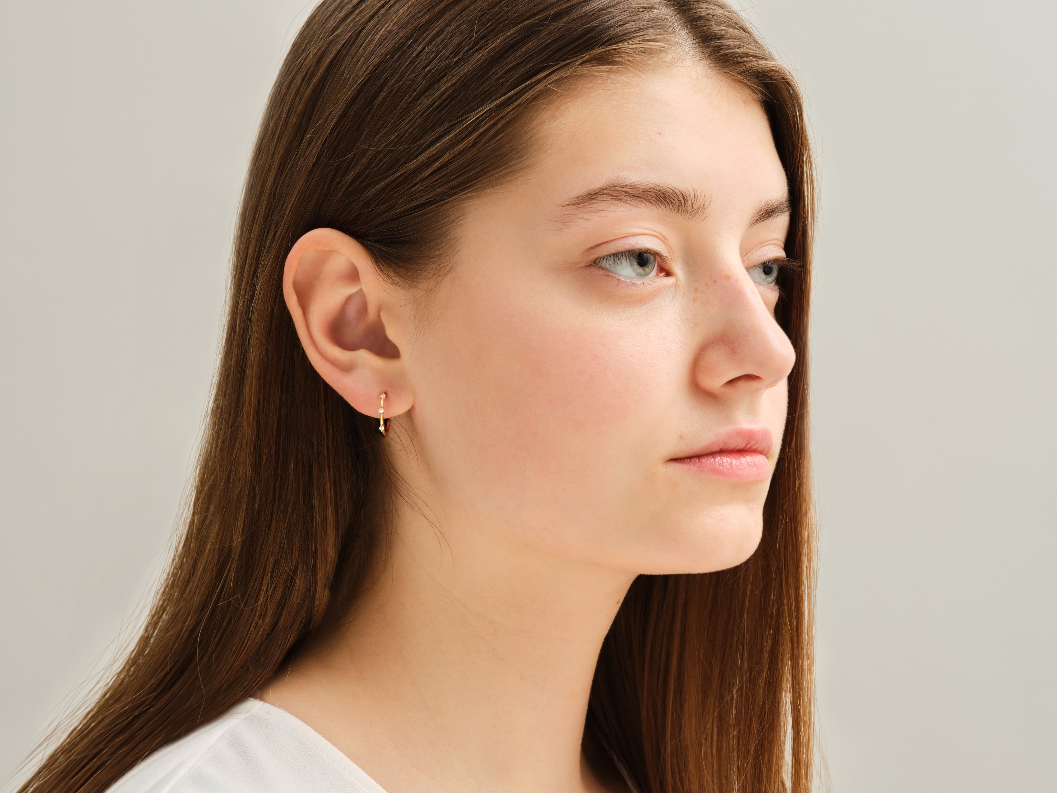 Diamond hoop earring on a young woman's ear, jewelry photography