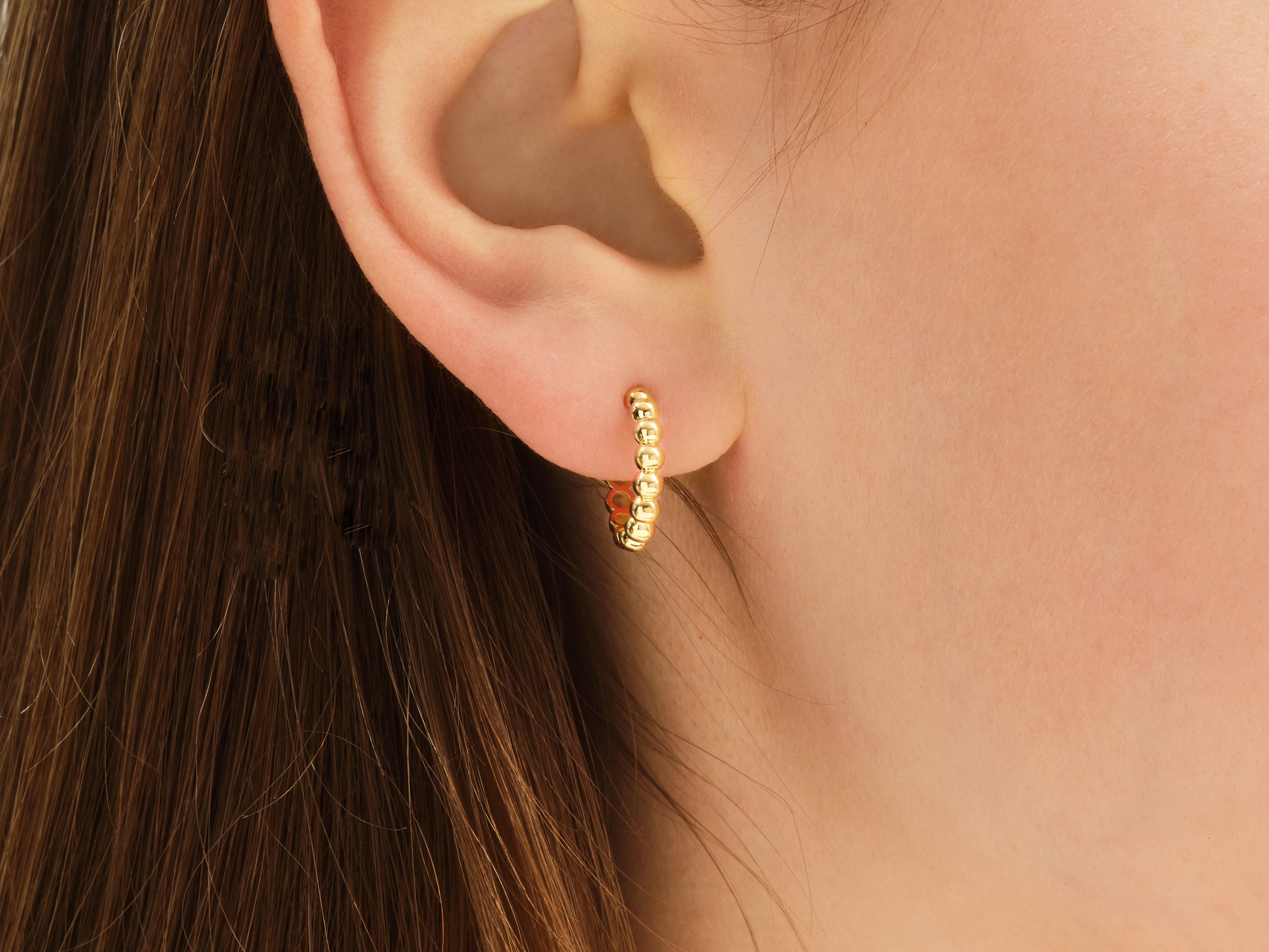Gold beaded hoop earring on ear, jewelry for women