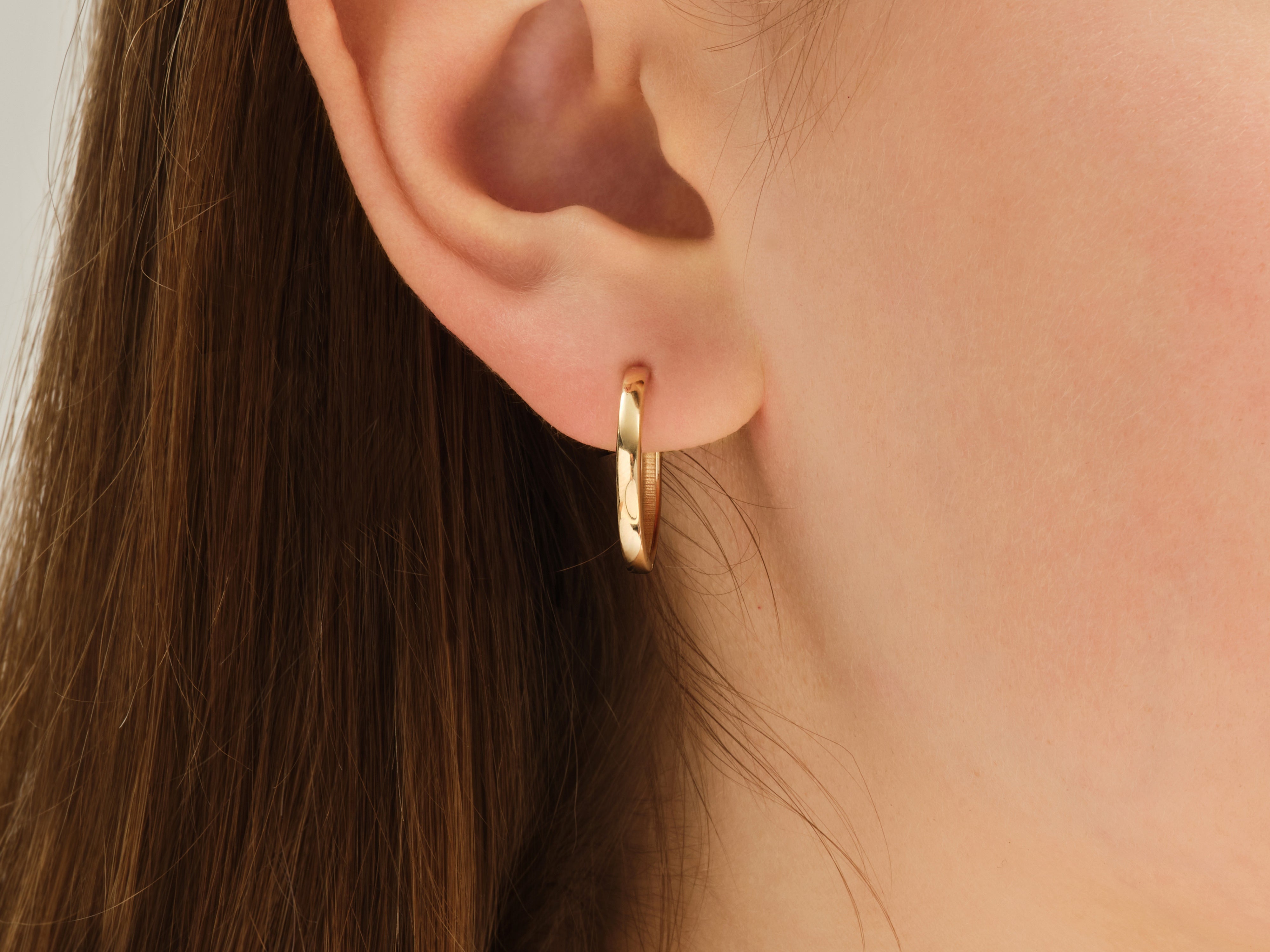 Gold hoop earring on a woman's ear, jewelry product