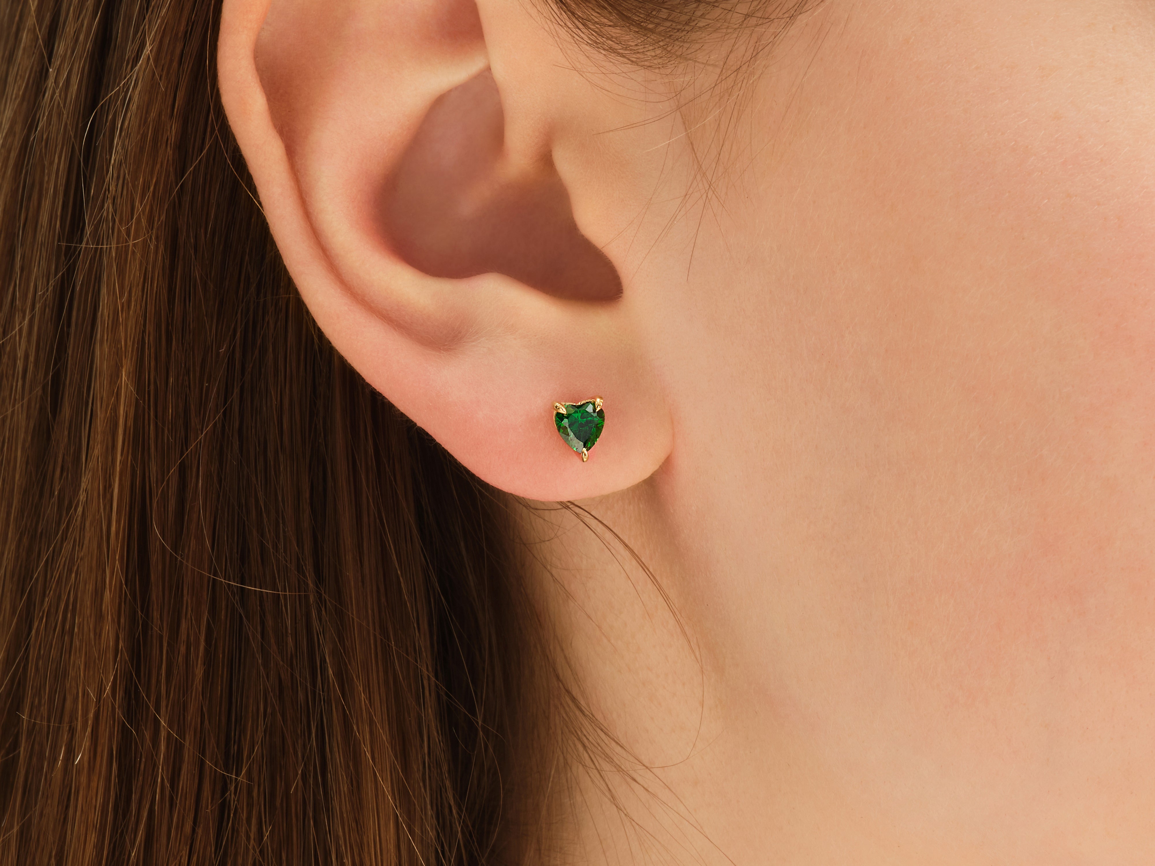 Heart-shaped emerald stud earring on ear, fine jewelry