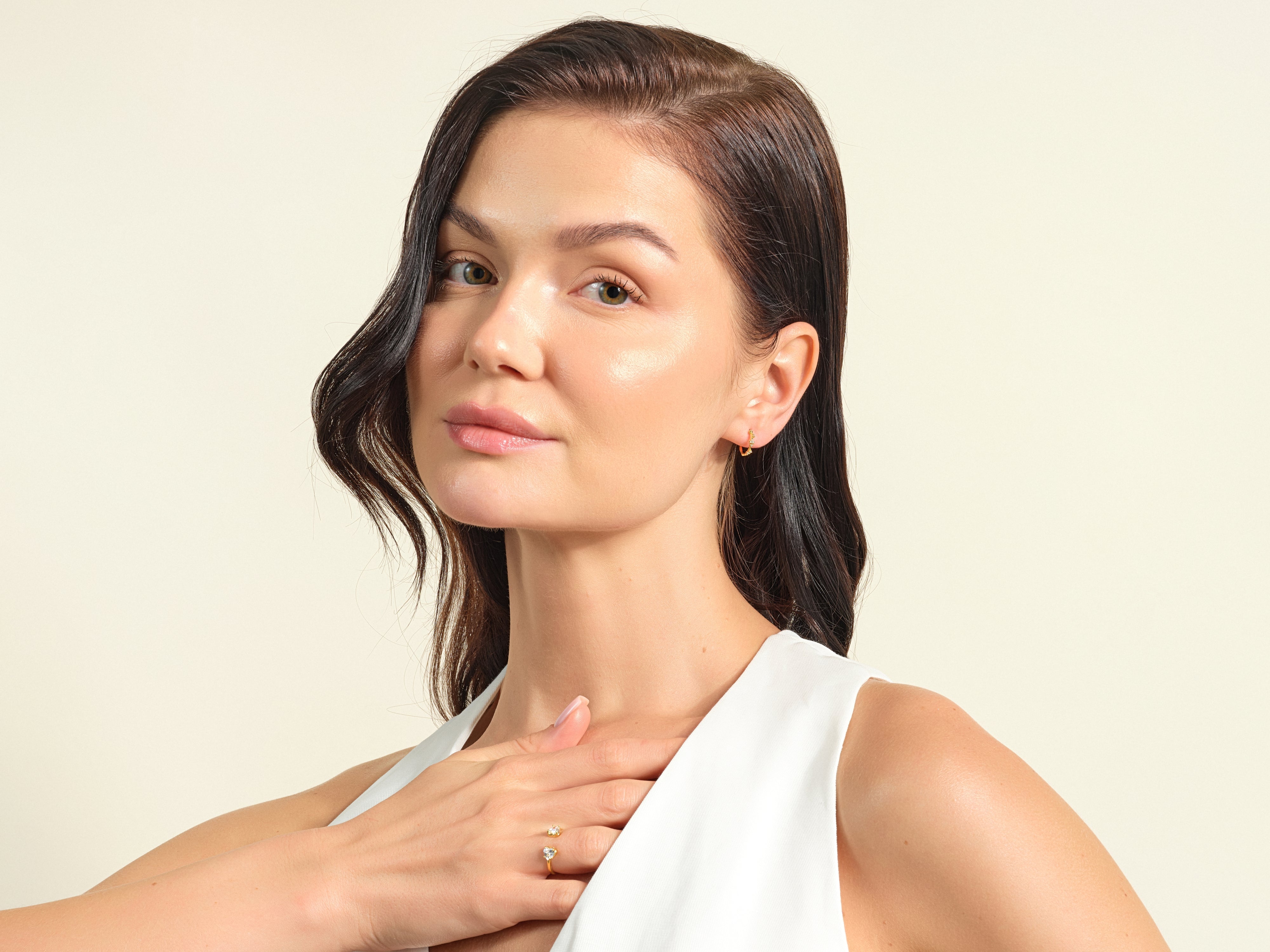 Woman wearing elegant gold ring and earrings, showcasing fine jewelry