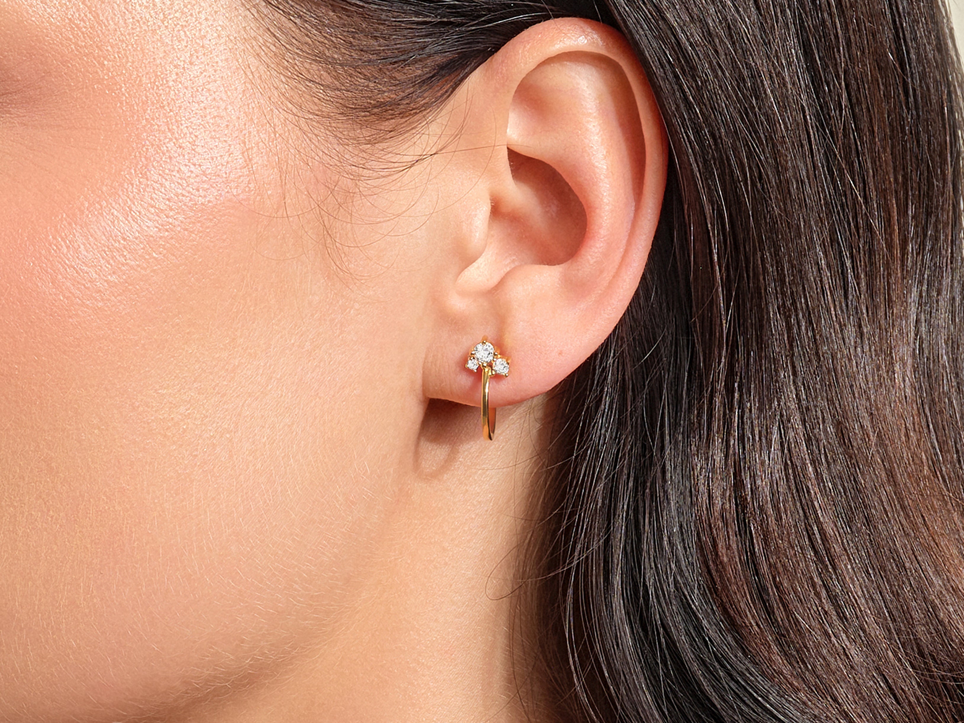 Gold hoop earring with three diamonds on a woman's ear