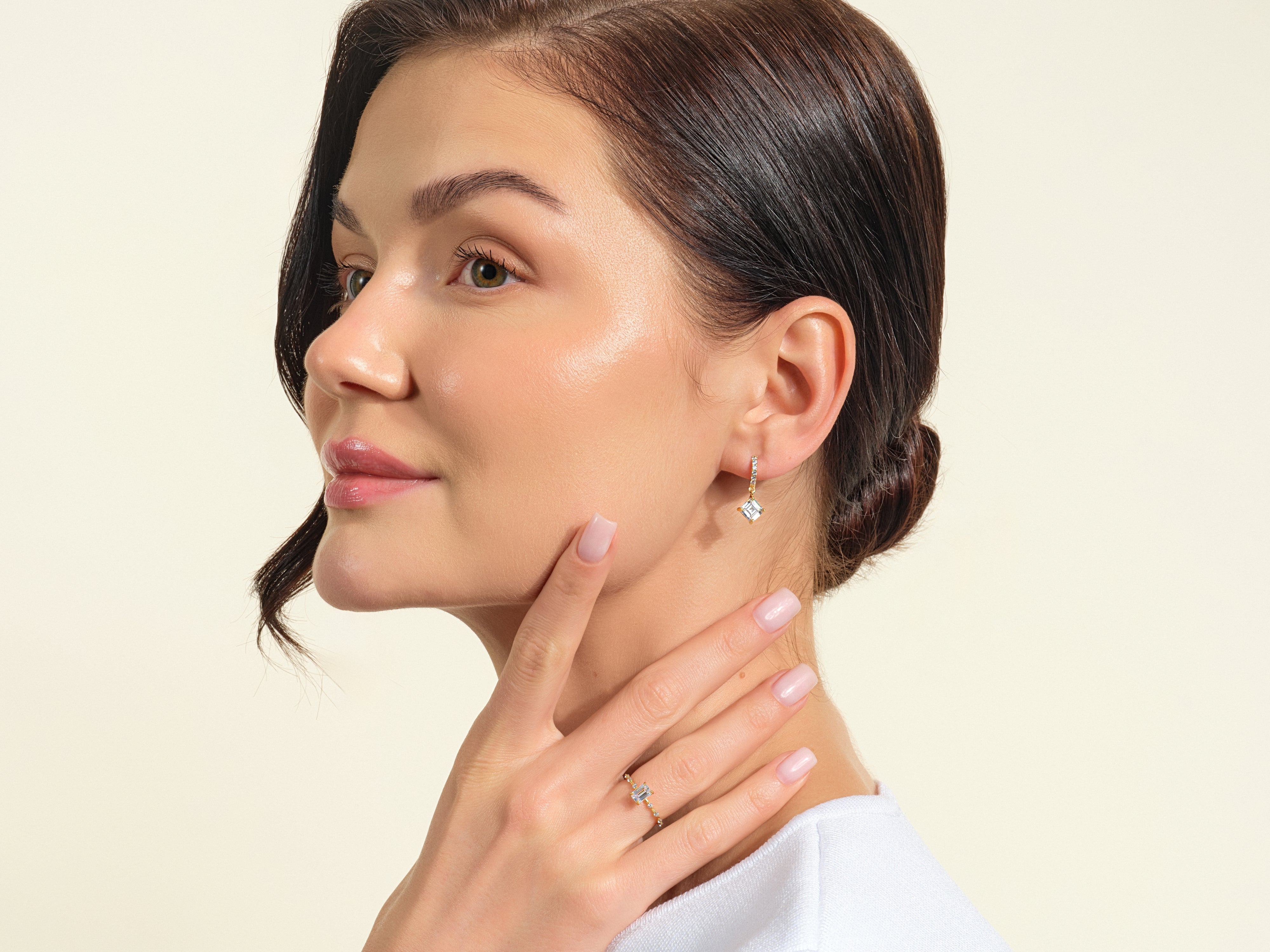 Woman wearing diamond earrings and ring, showcasing fine jewelry