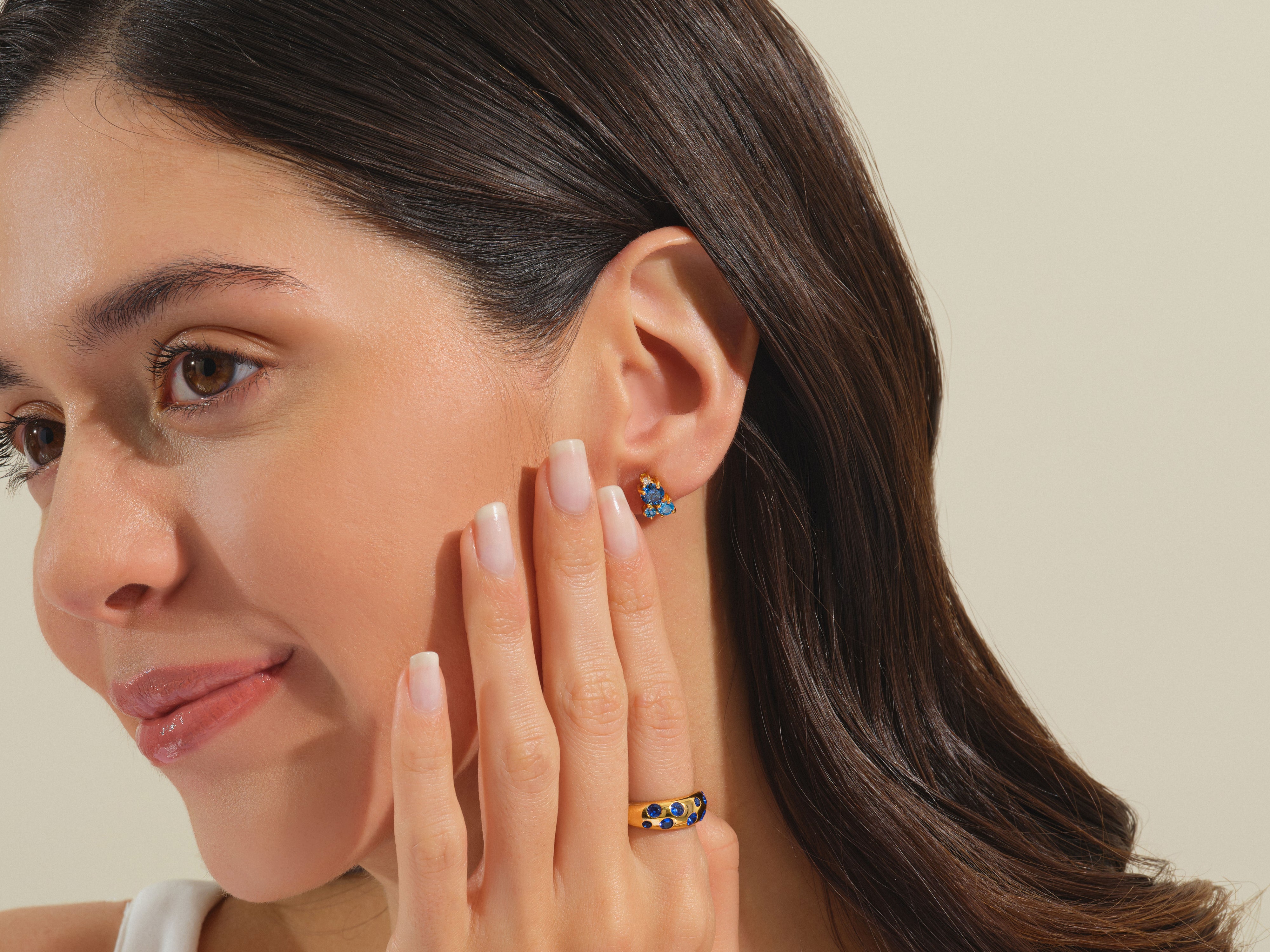 Woman wearing gold sapphire butterfly earrings and ring