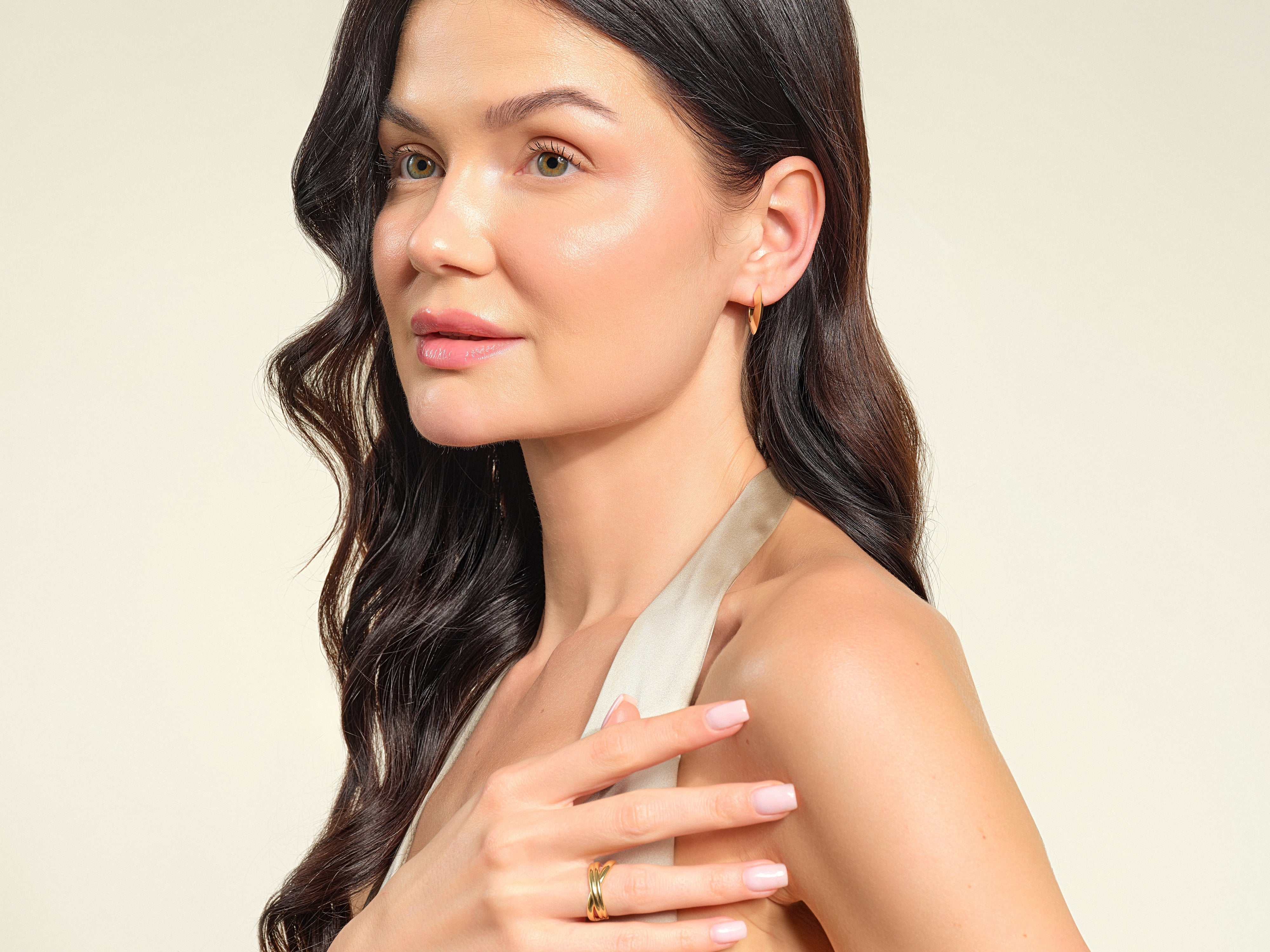 Woman wearing elegant gold hoop earrings and a layered ring