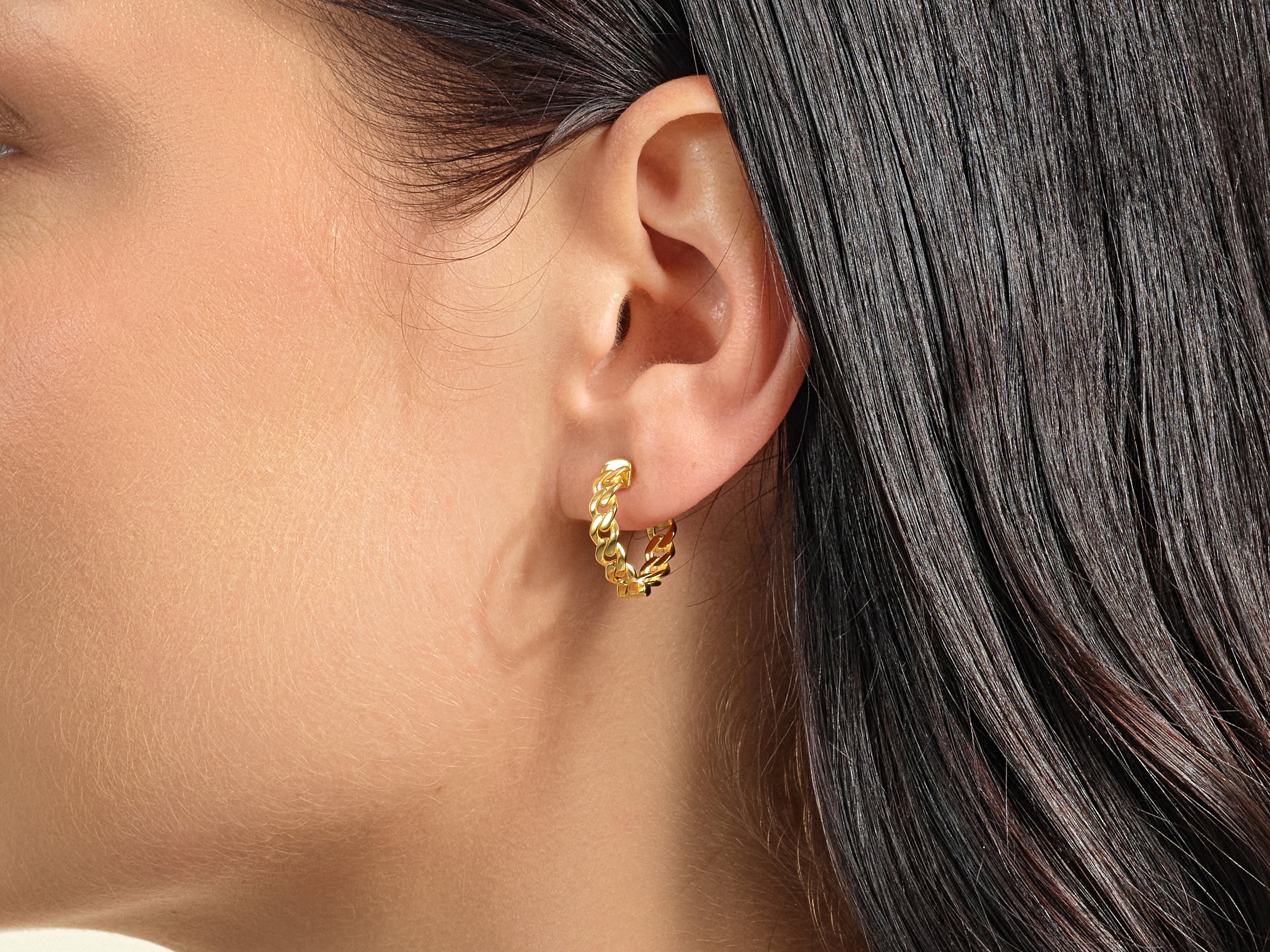 Gold curb chain hoop earring on a woman's ear