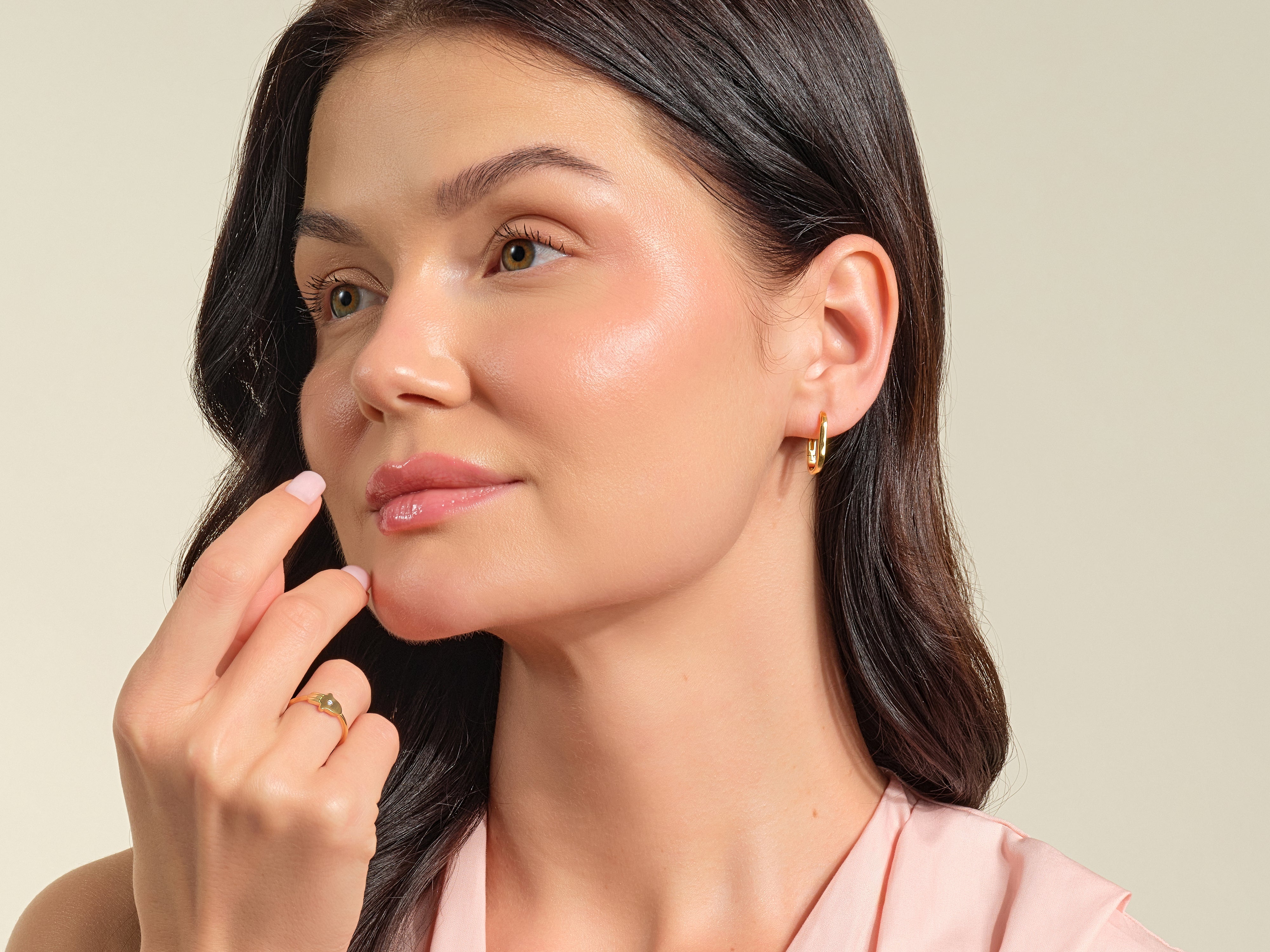 Woman wearing gold hoop earrings and a delicate ring