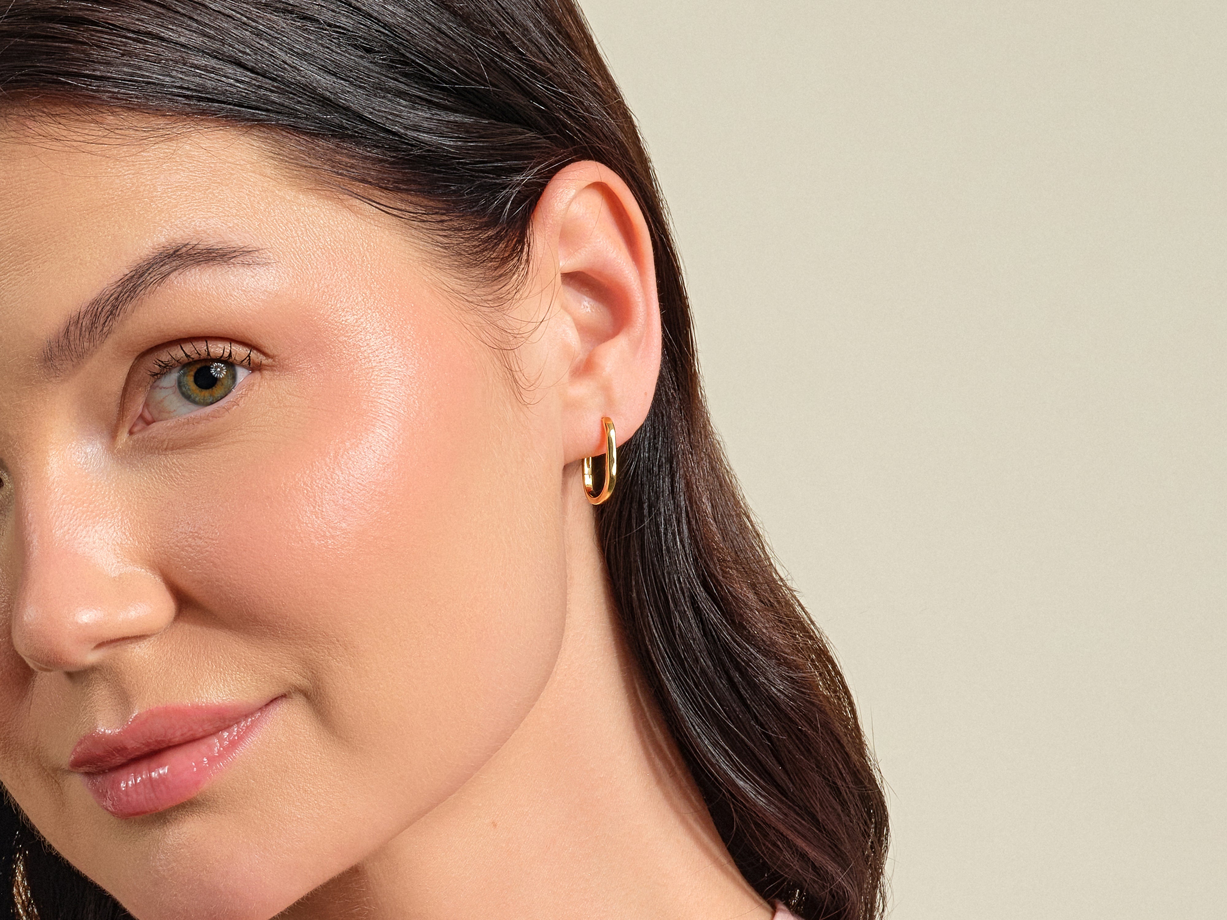 Gold oval hoop earrings on a woman's ear, jewelry photography