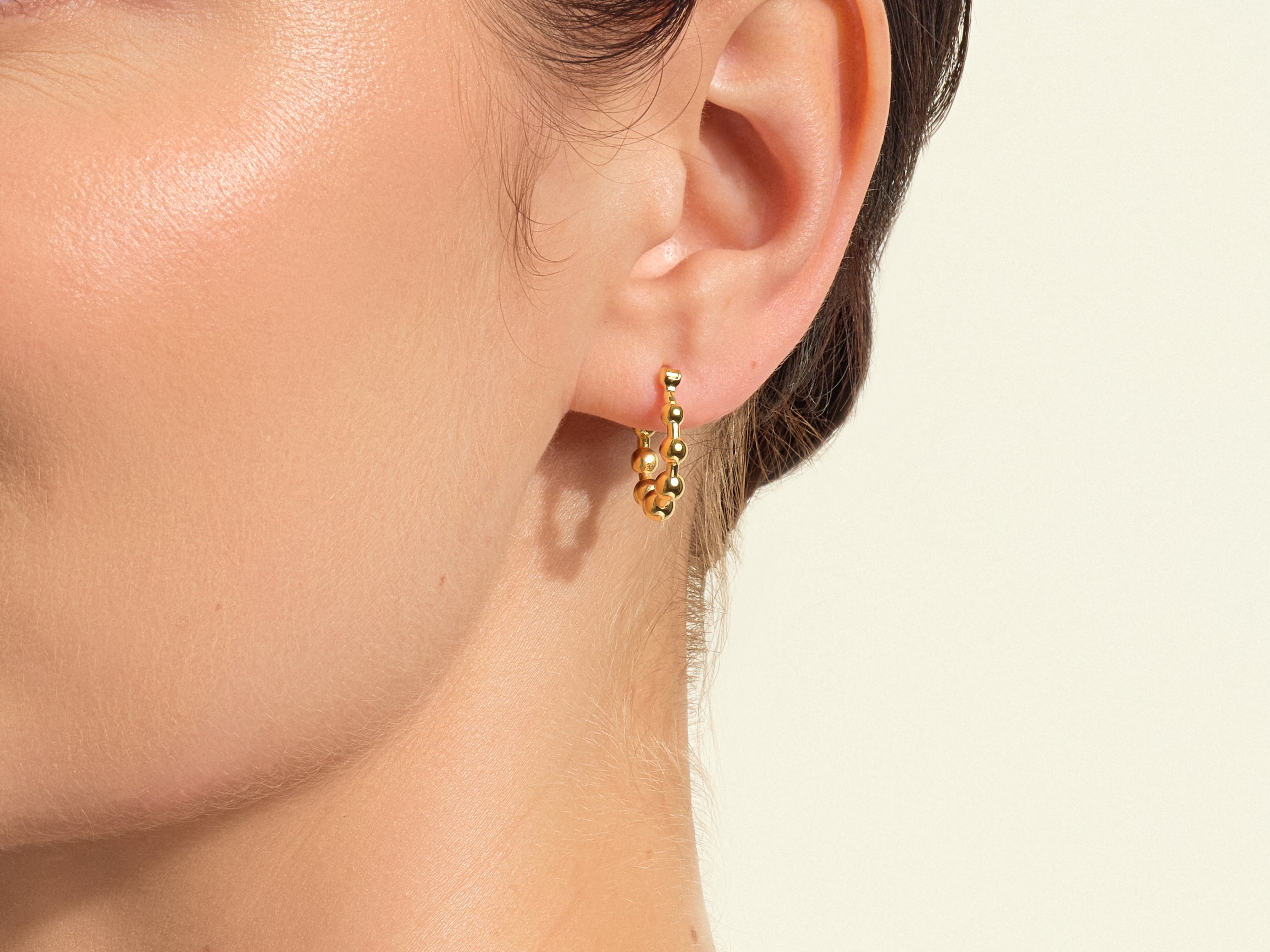 Gold beaded hoop earring on ear, jewelry