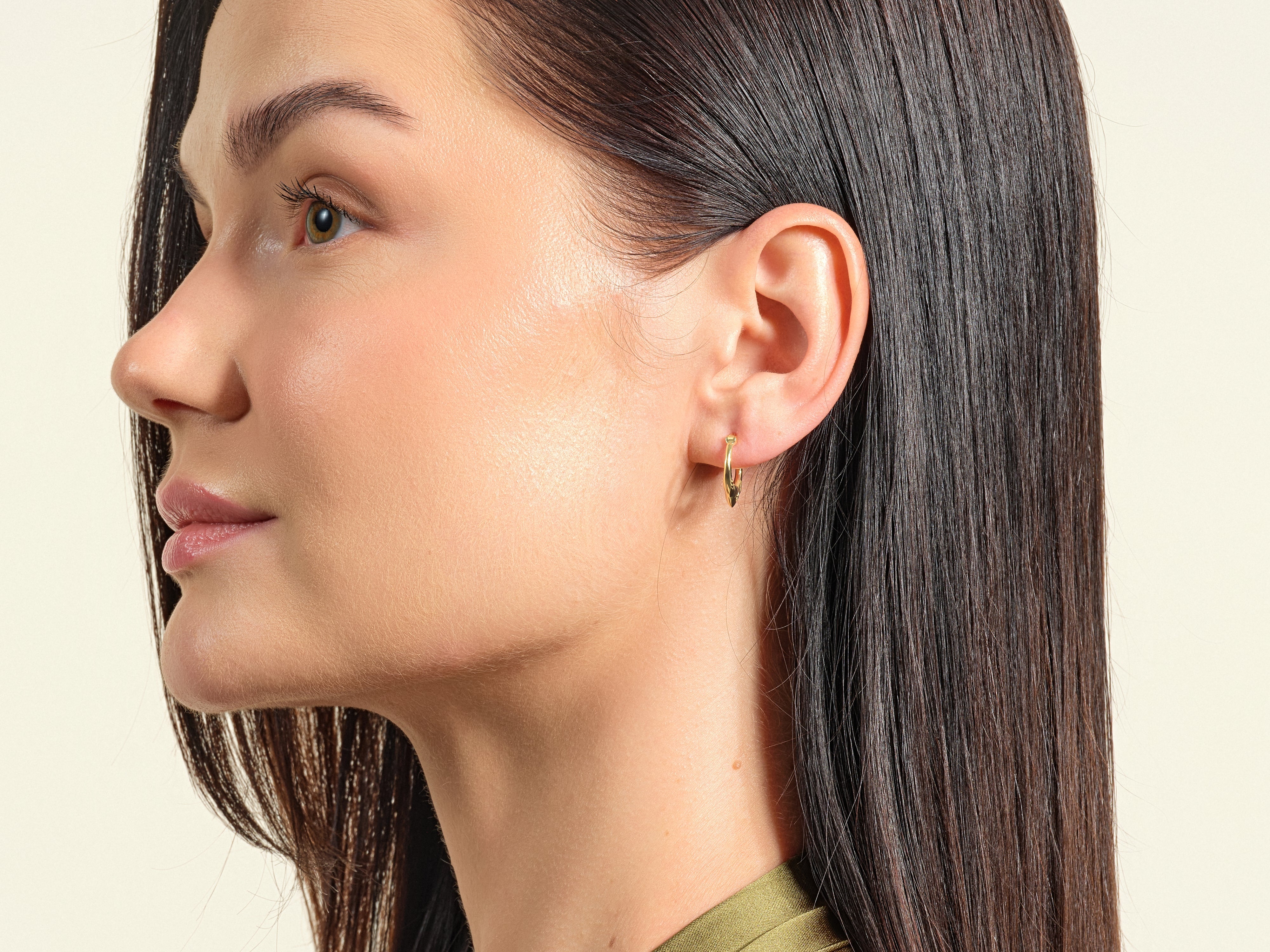 Gold hoop earring on a woman's ear, showcasing fine jewelry detail