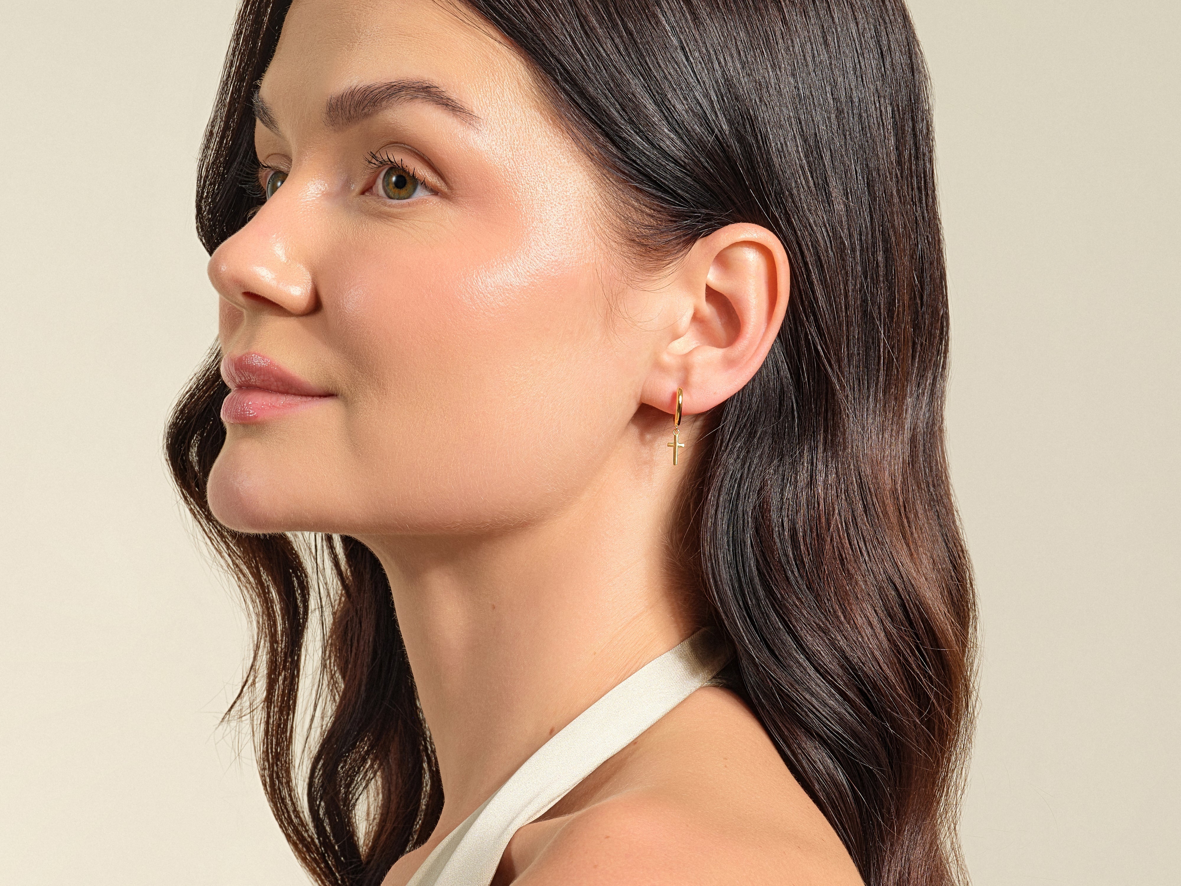 Gold cross earring on a woman's ear, jewelry product