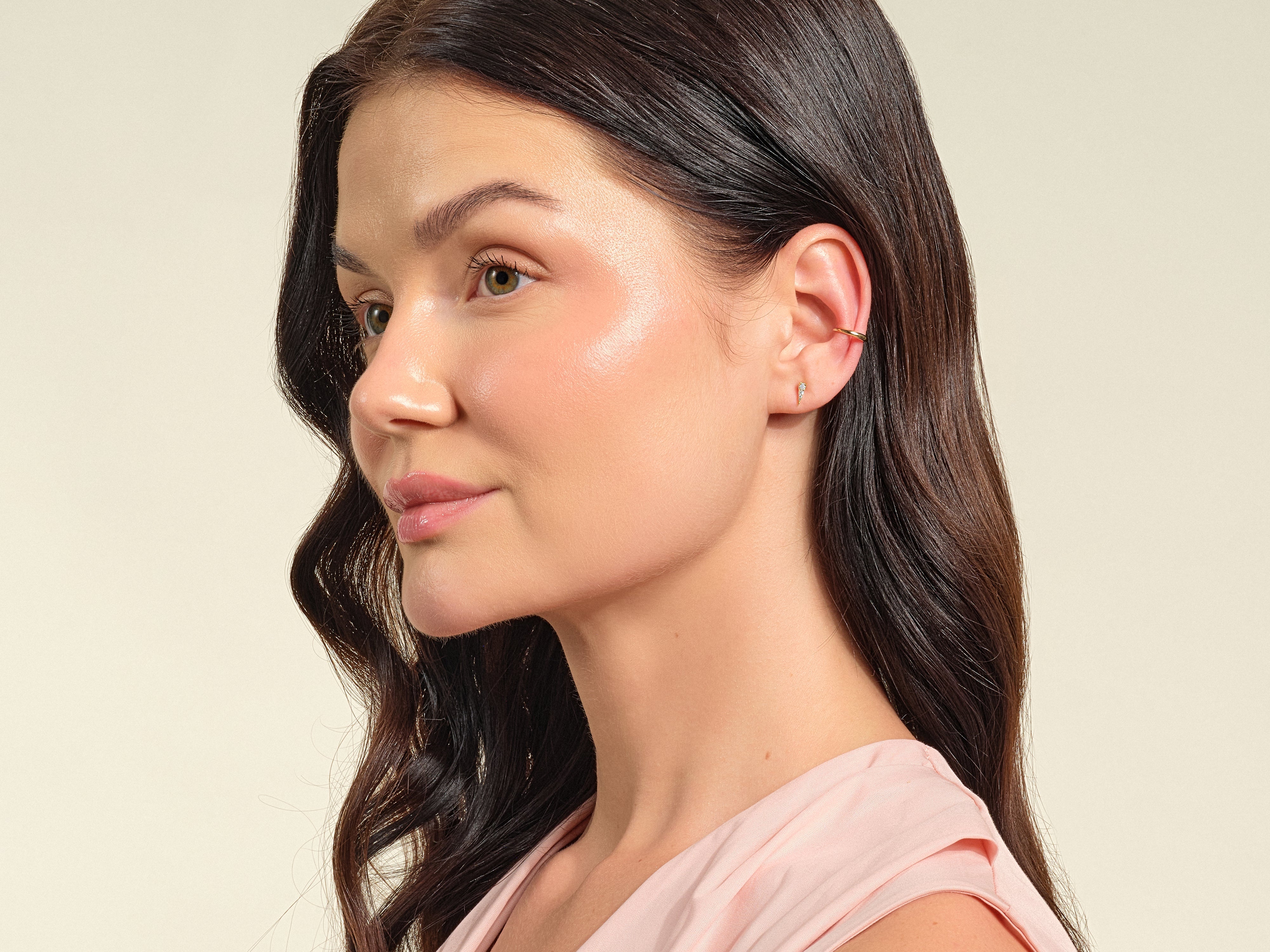 Woman wearing delicate gold ear cuff and stud earrings