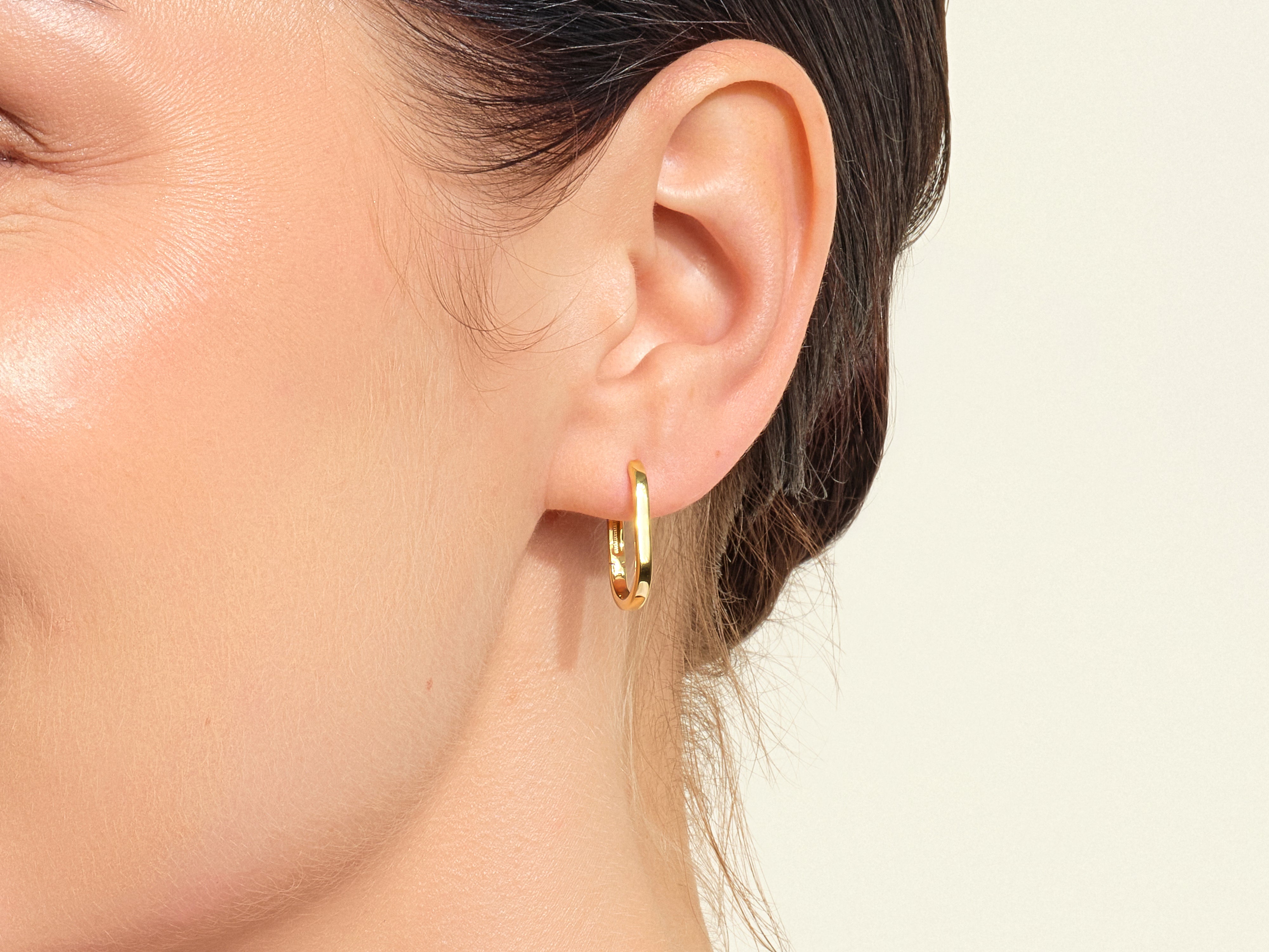 Gold hoop earring on a woman's ear, jewelry product photography