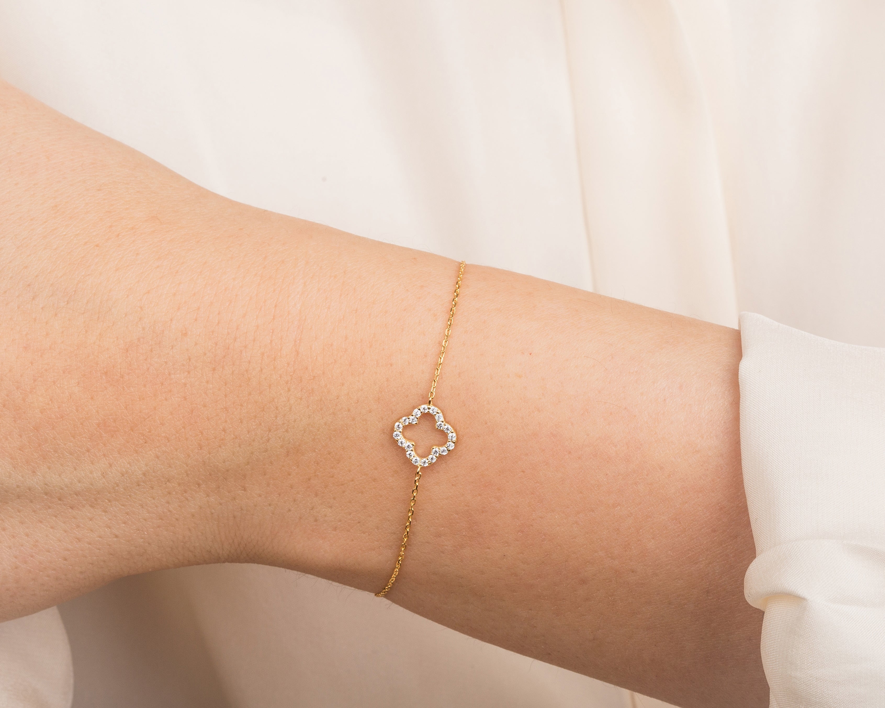 Gold clover bracelet with diamonds on a woman's wrist