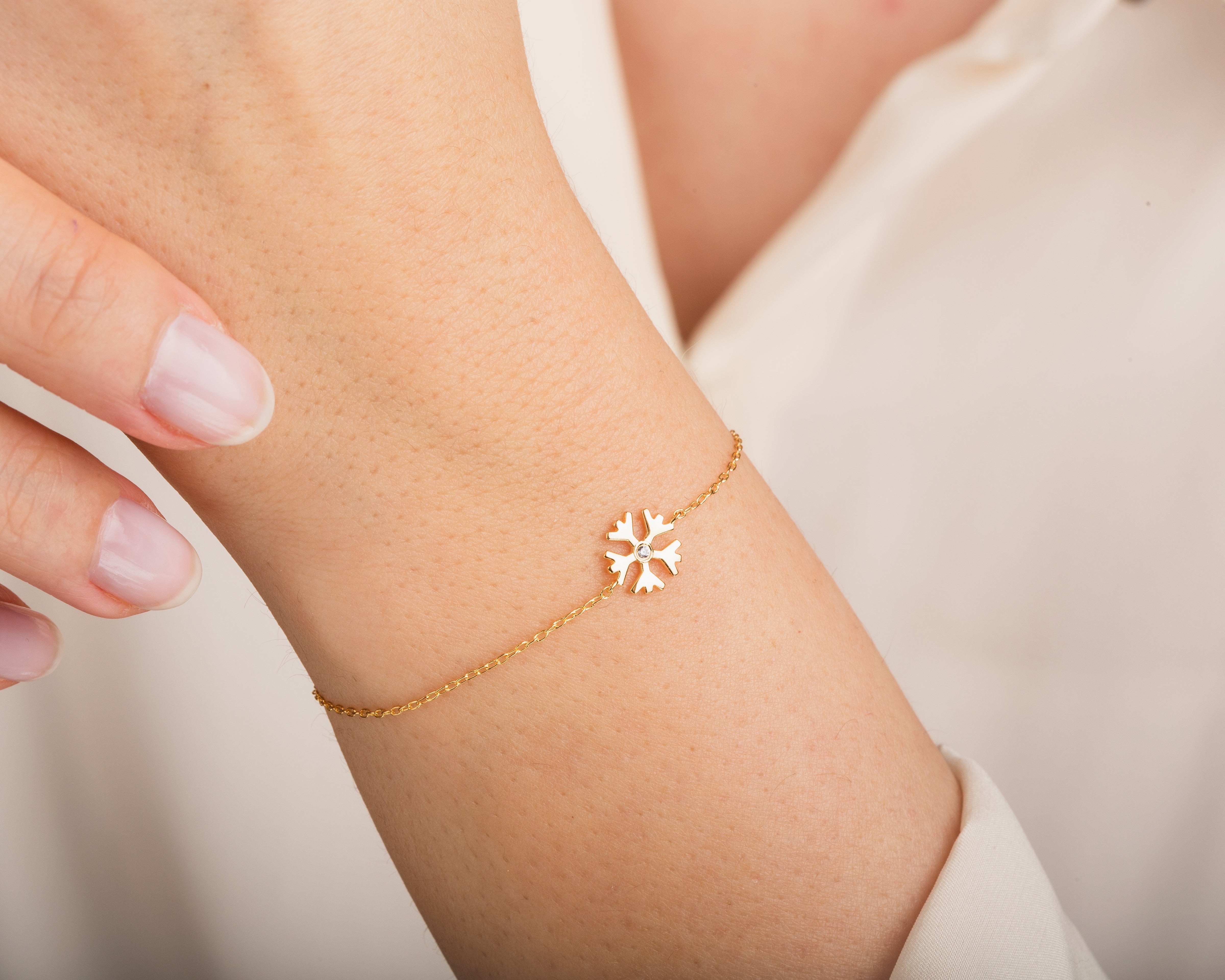 Gold snowflake bracelet with diamond accent on wrist