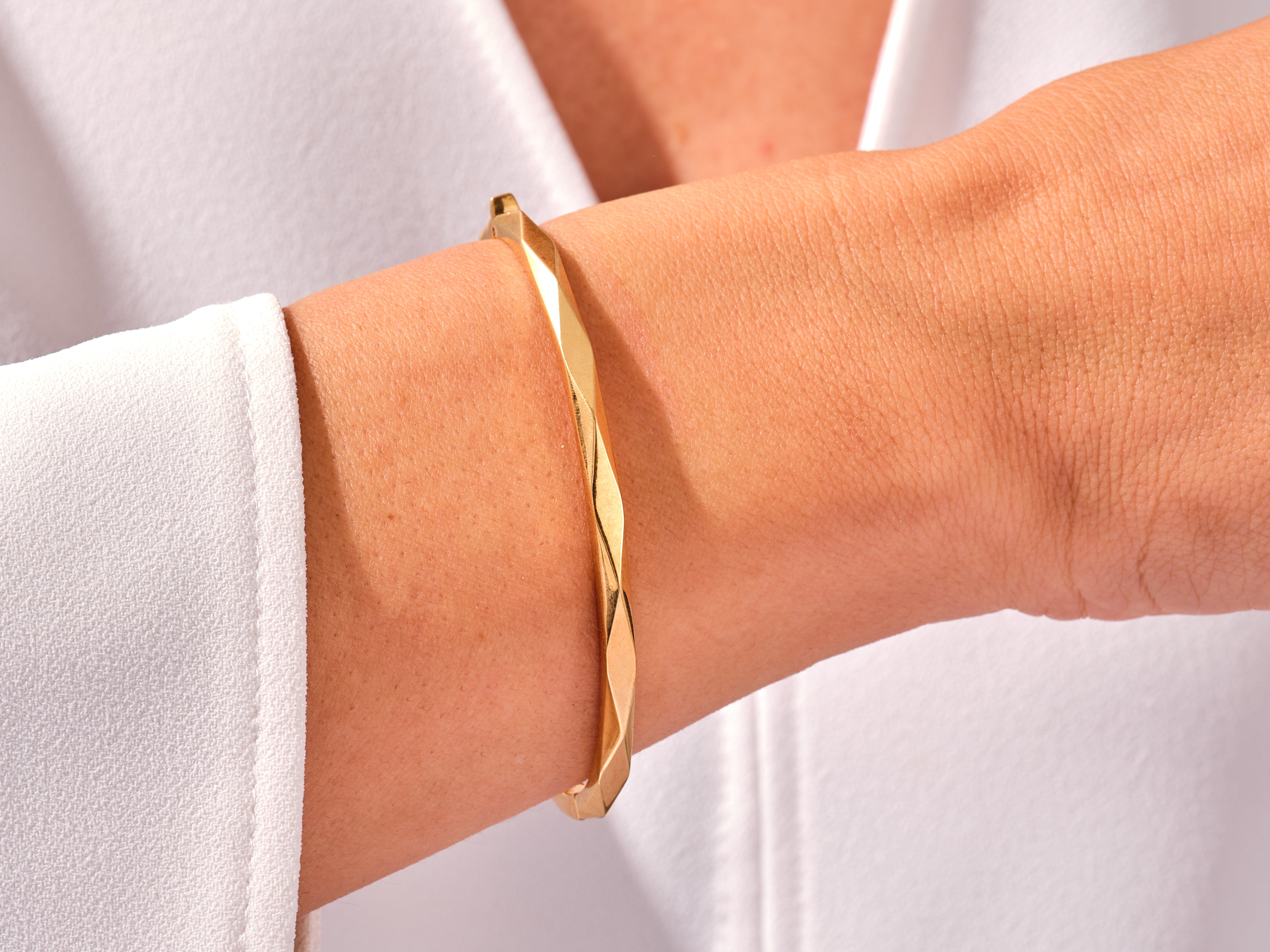 Gold twisted bangle bracelet on a woman's wrist