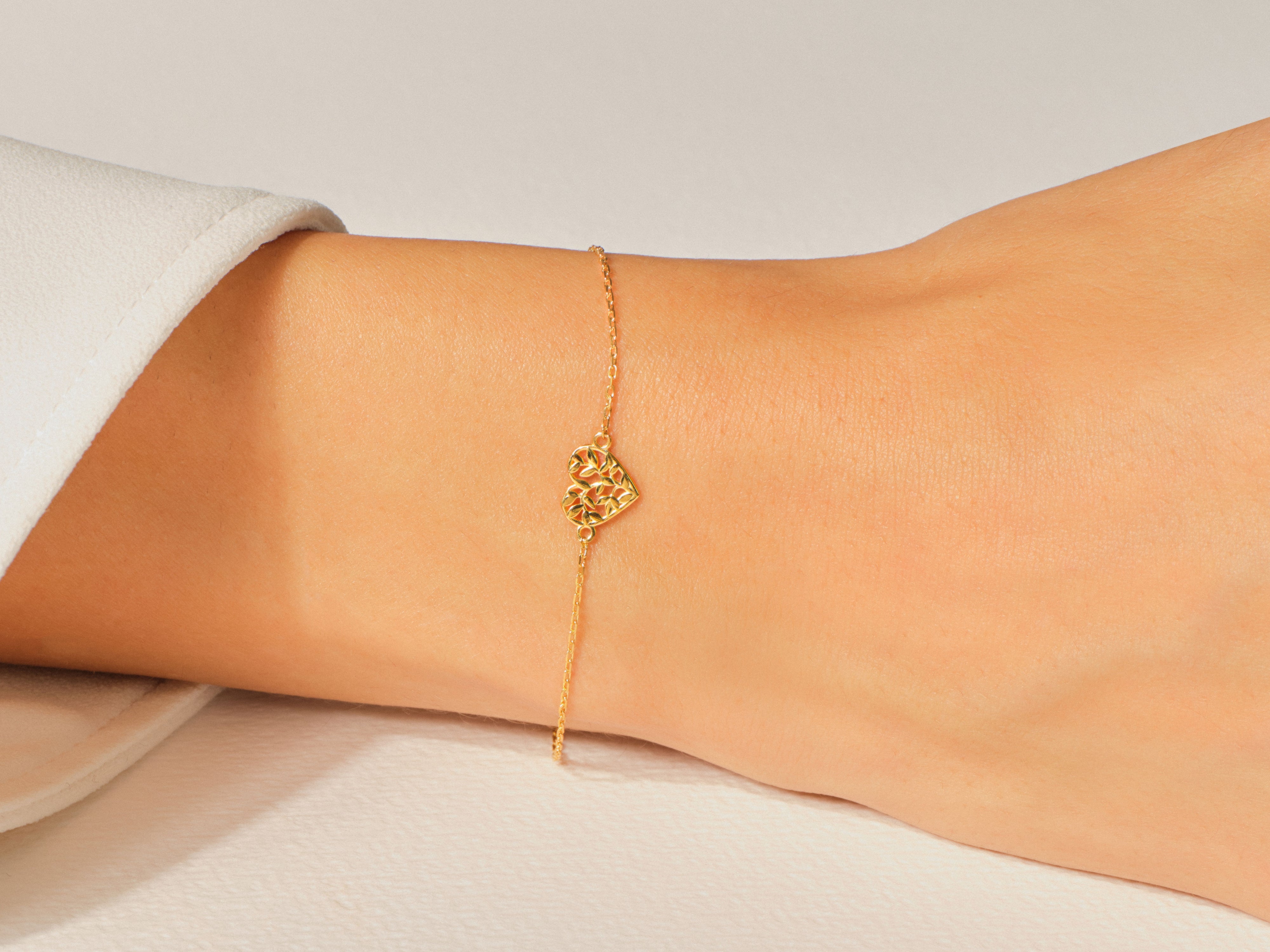 Gold heart charm bracelet on a woman's wrist