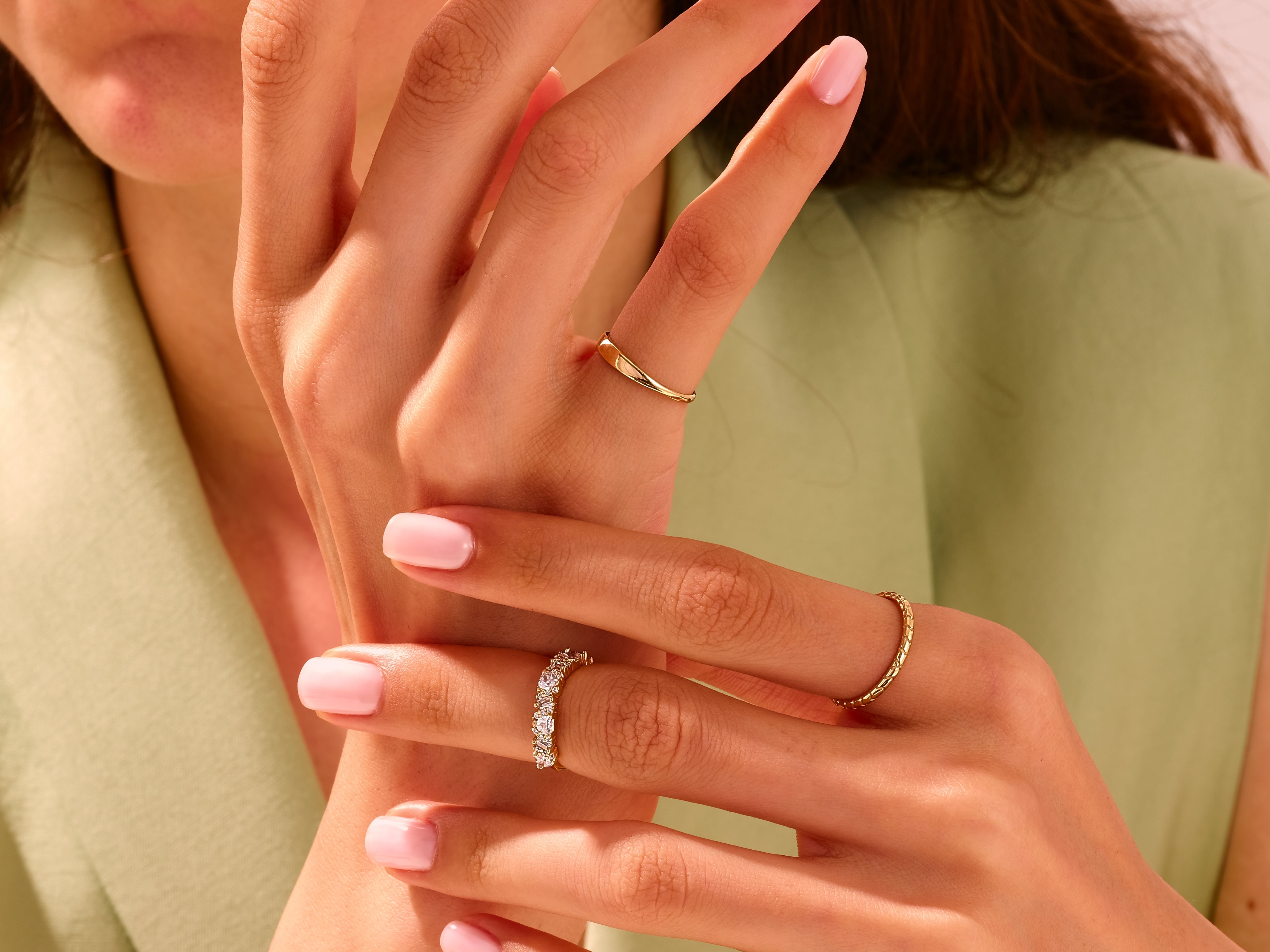Gold rings with diamonds and textured band on manicured hand