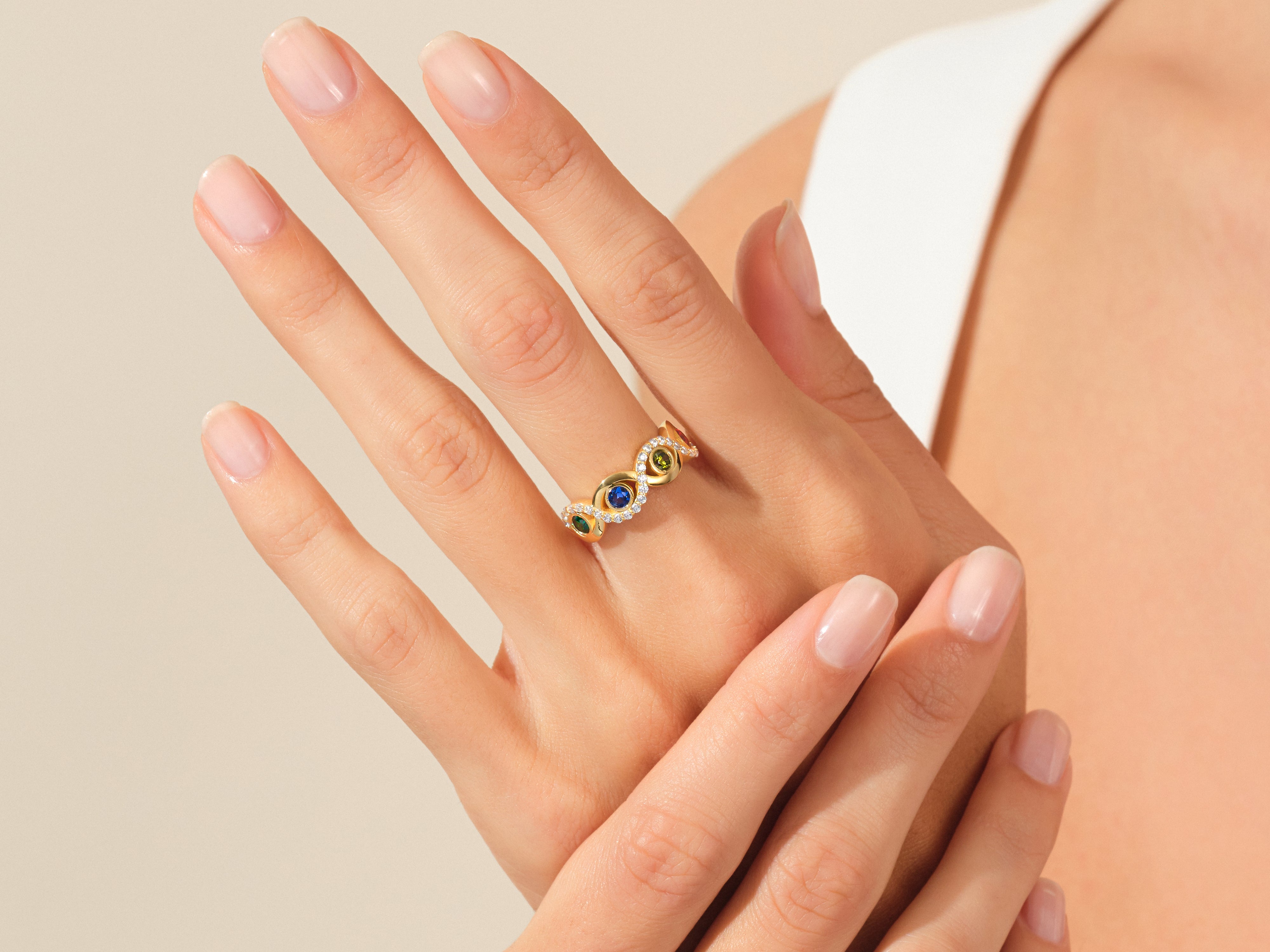 Gold ring with colorful gemstones and diamonds on a woman's hand