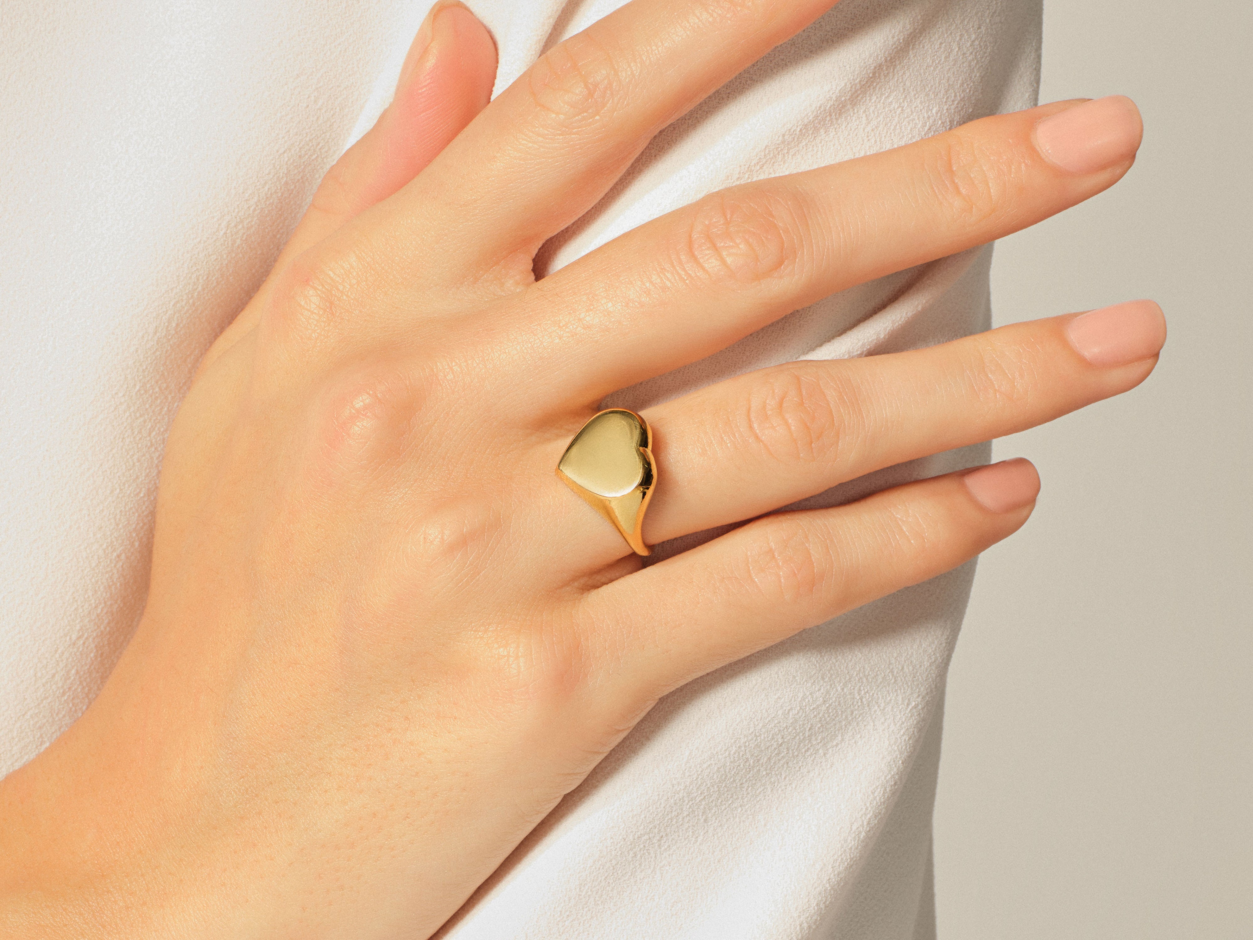 Gold heart ring on a woman's finger, elegant jewelry