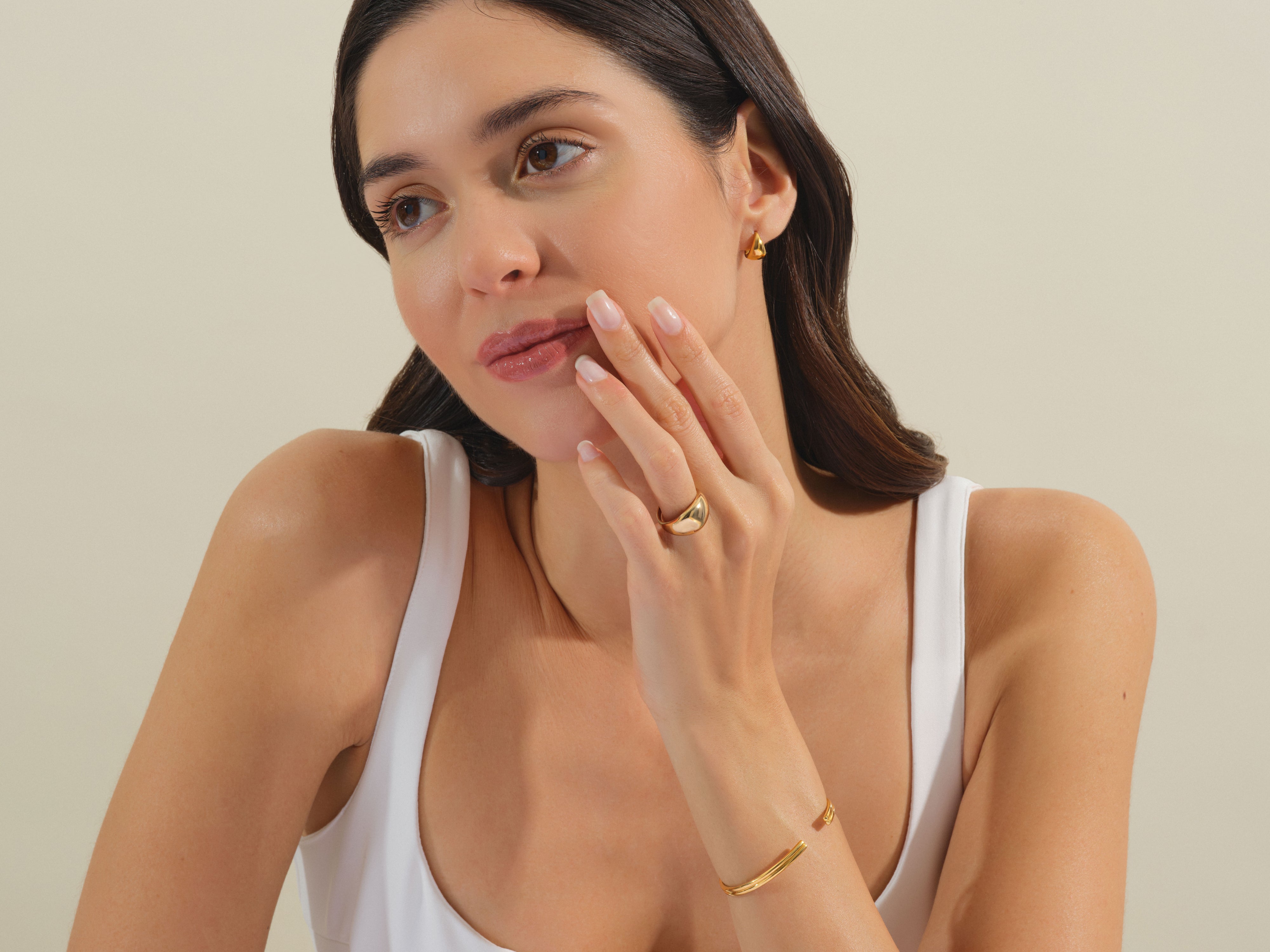 Model wearing gold jewelry: earrings, ring, and bracelet