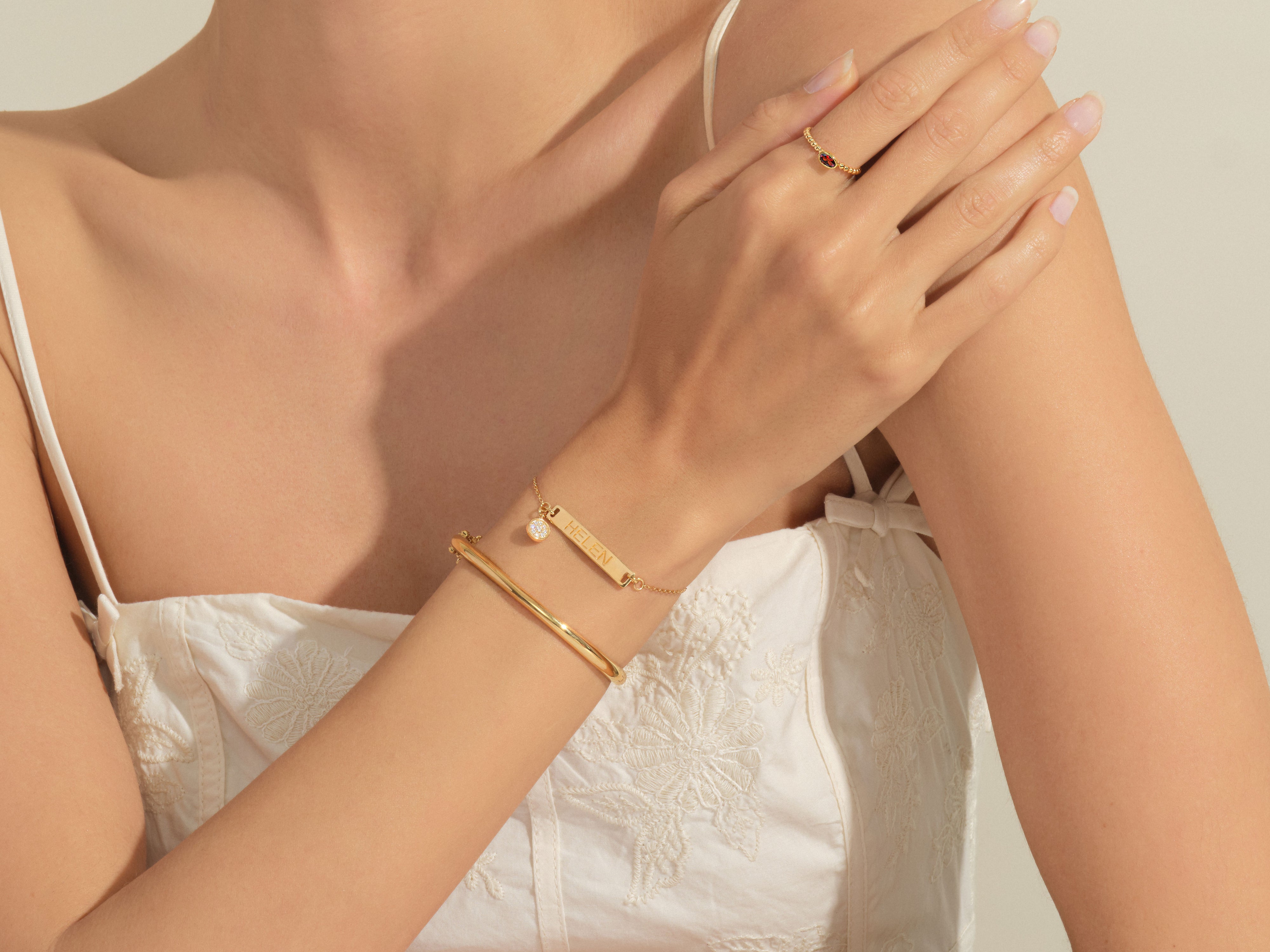 Gold jewelry on woman's arm: personalized bracelet and ruby ring