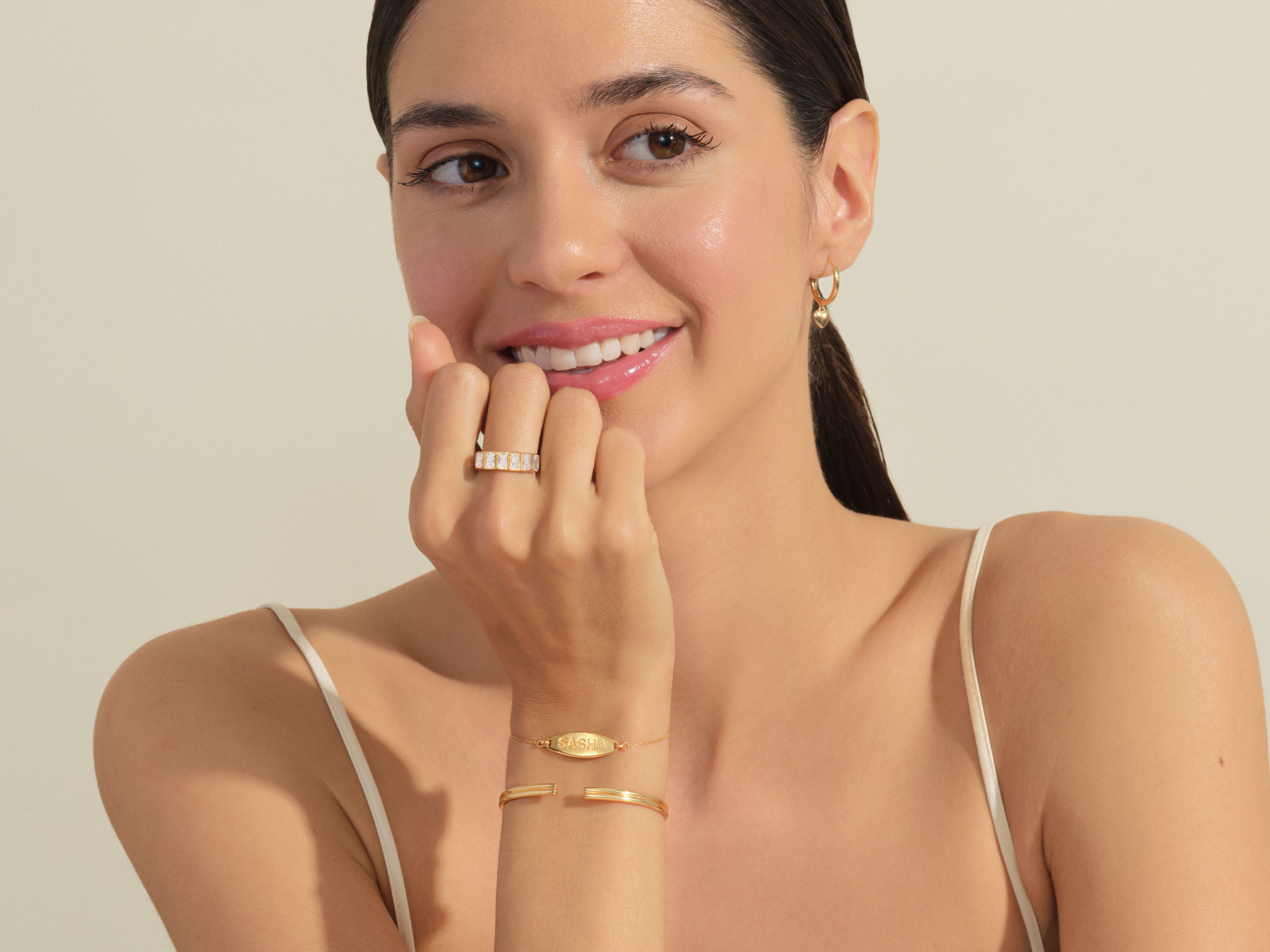 Woman wearing gold jewelry, diamond ring, and personalized bracelet