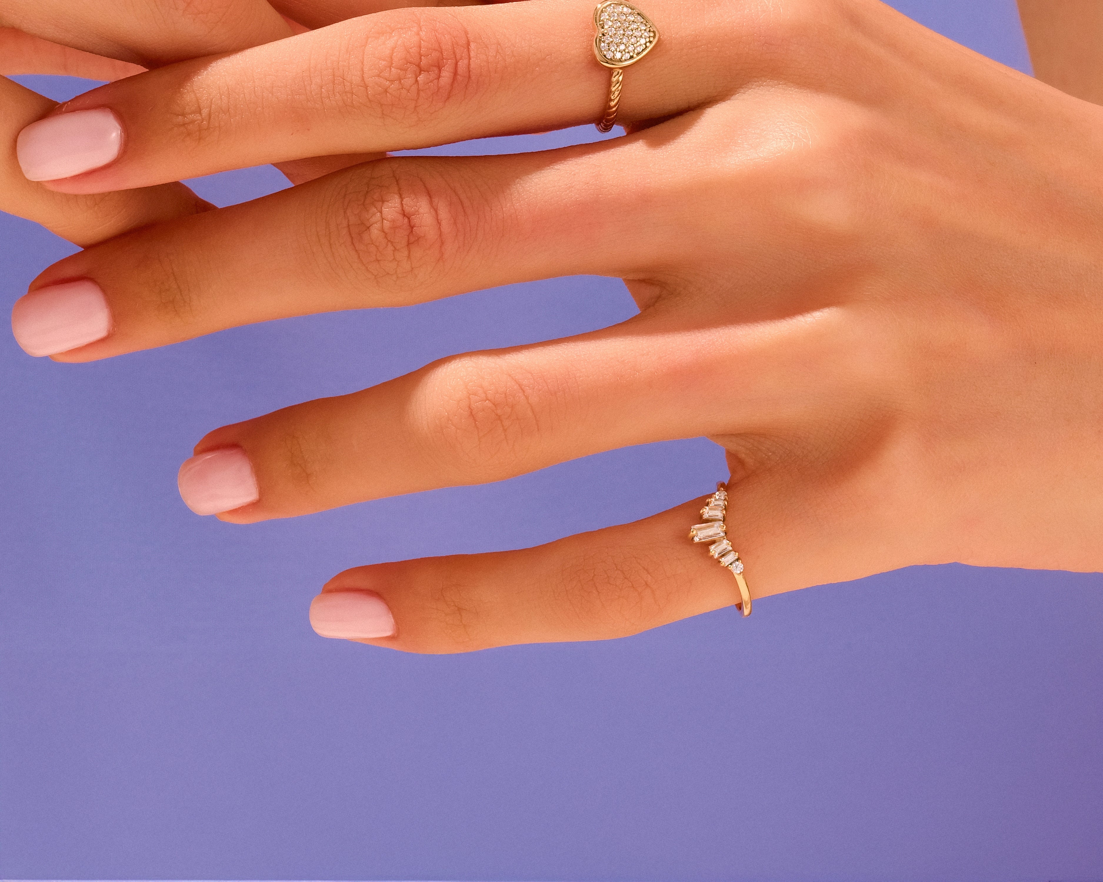Gold rings on hands, heart and baguette diamond designs
