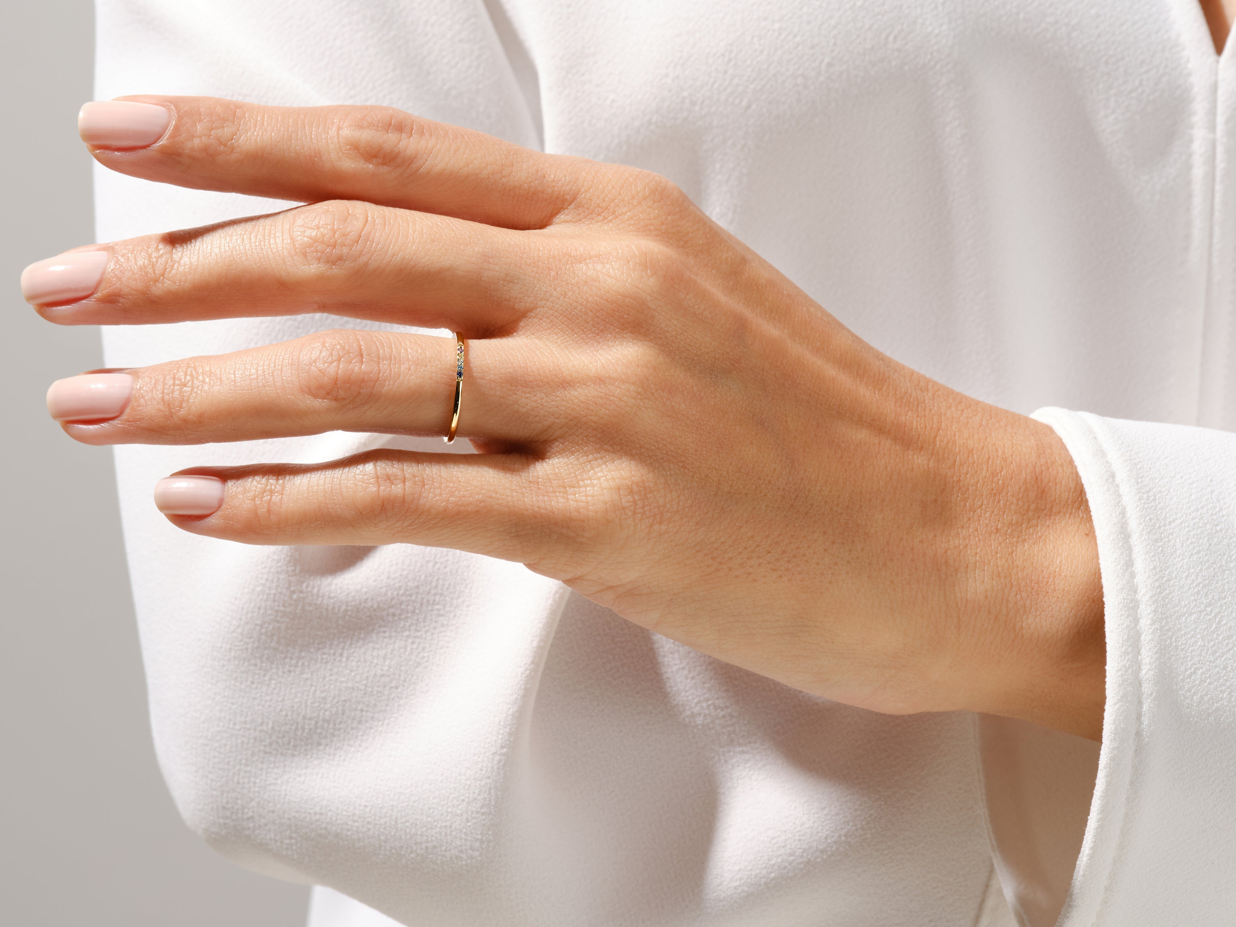 Delicate gold ring with colorful gemstones on a woman's hand