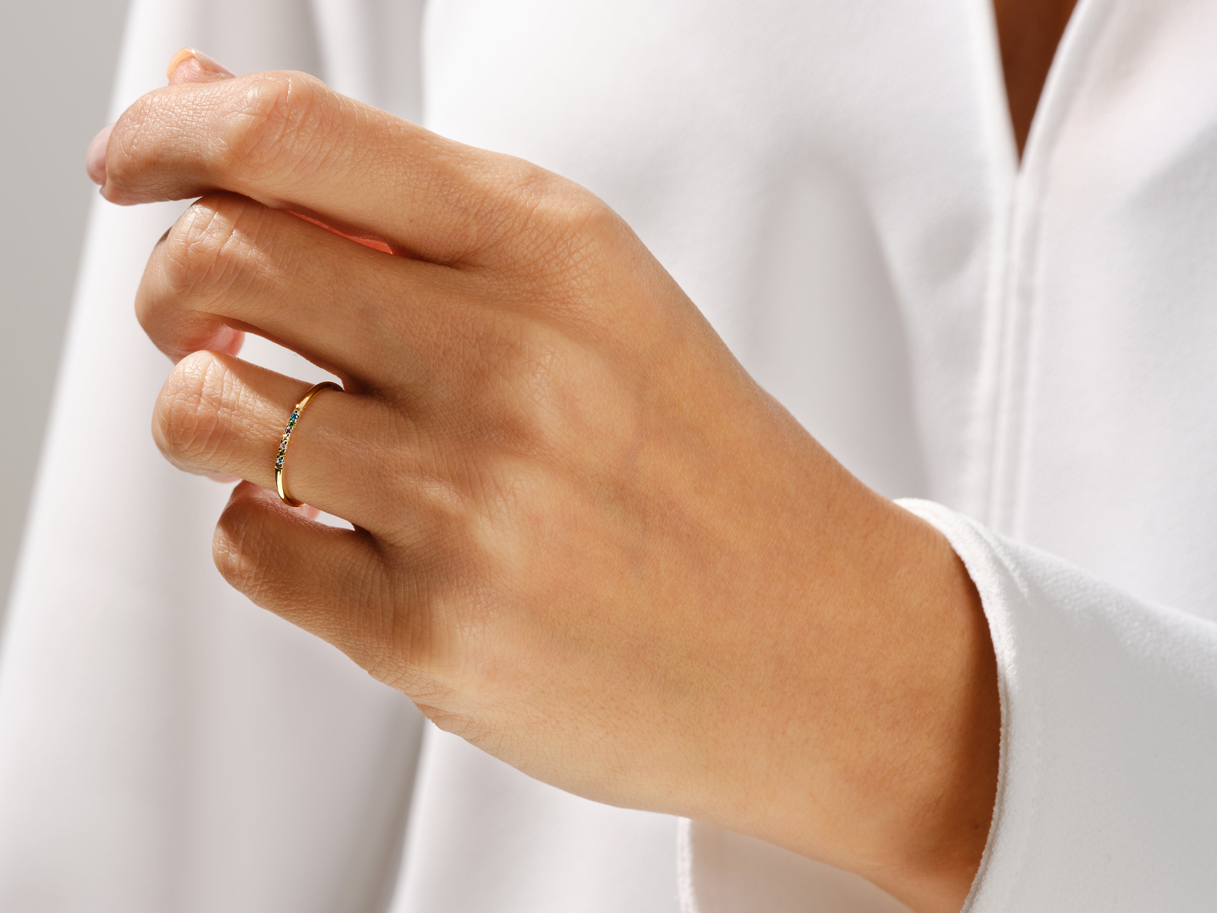 Delicate gold ring with colorful gemstones on a hand