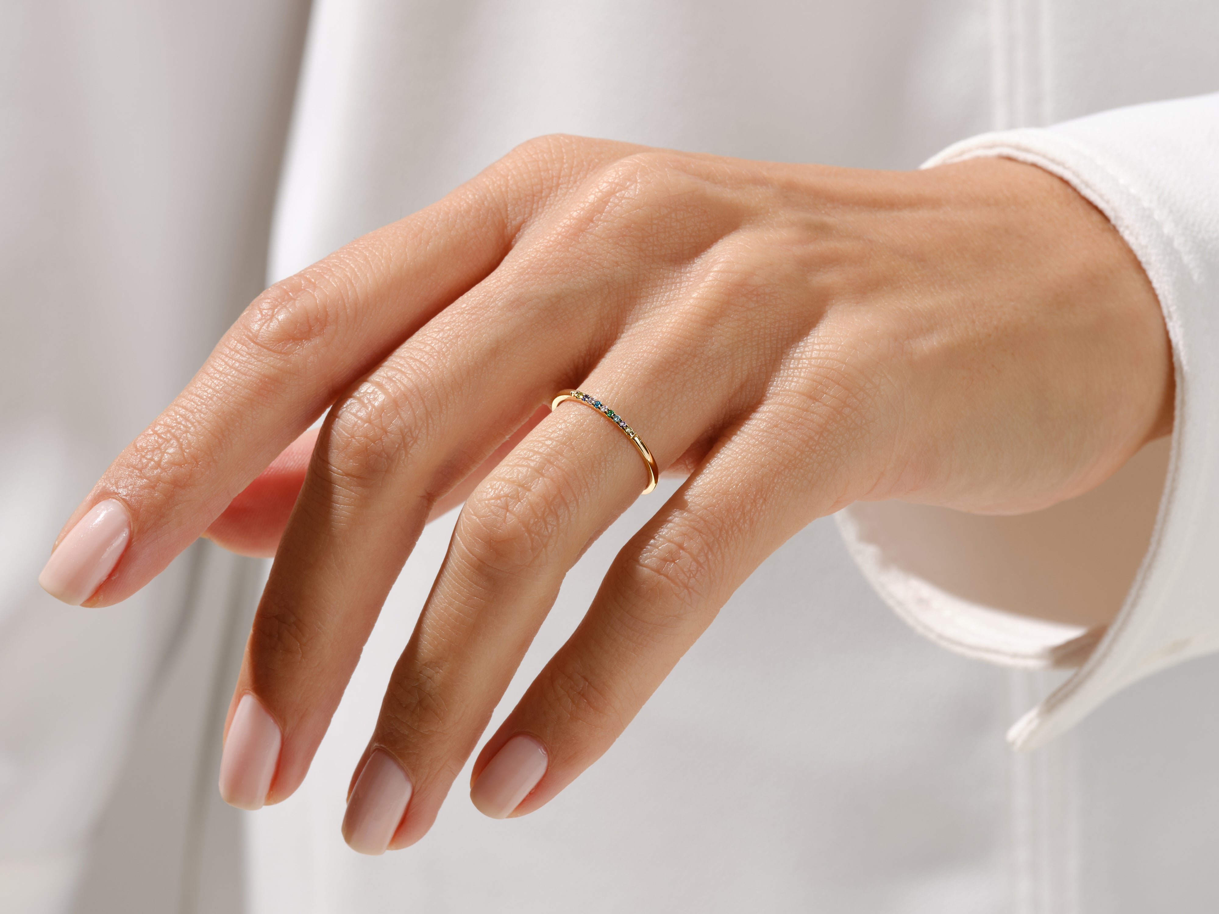 Delicate gold ring with colorful gemstones on a woman's hand