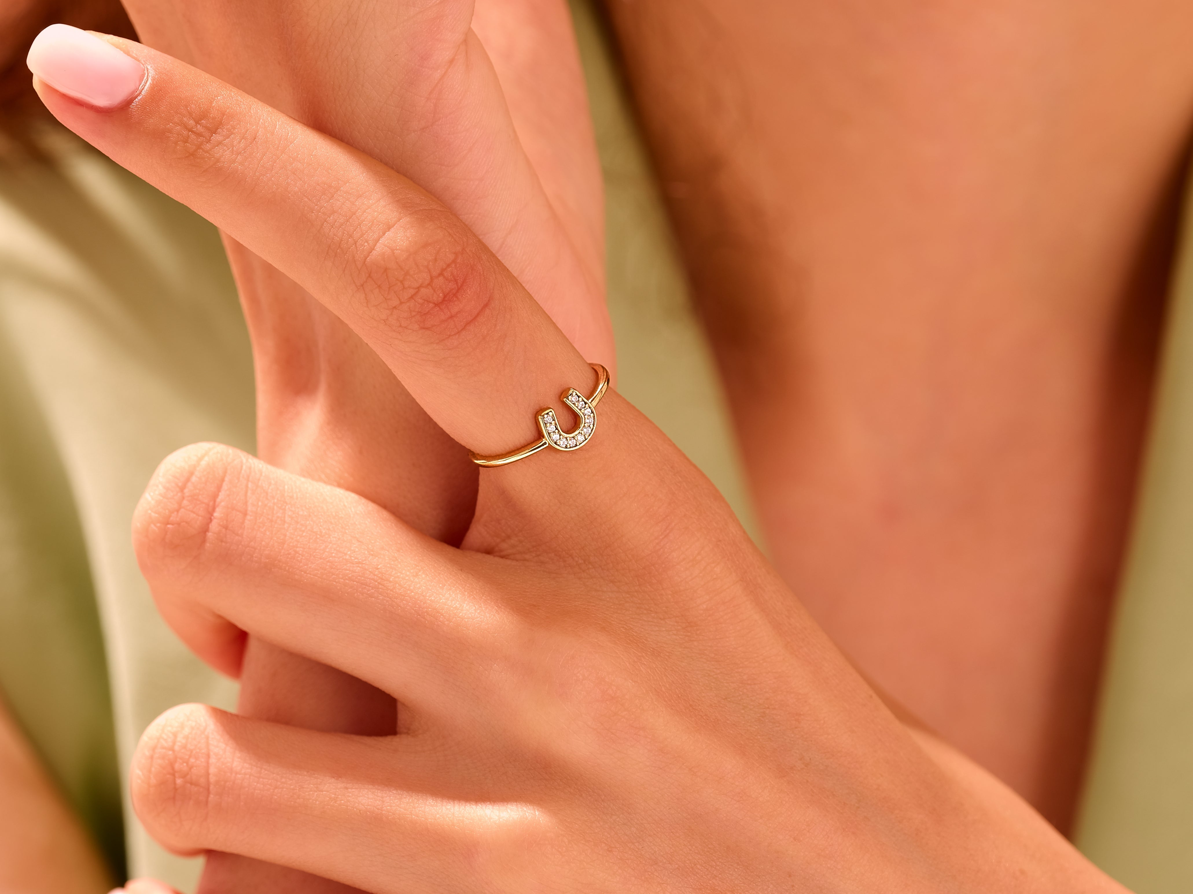 Gold horseshoe ring with diamonds on a woman's finger