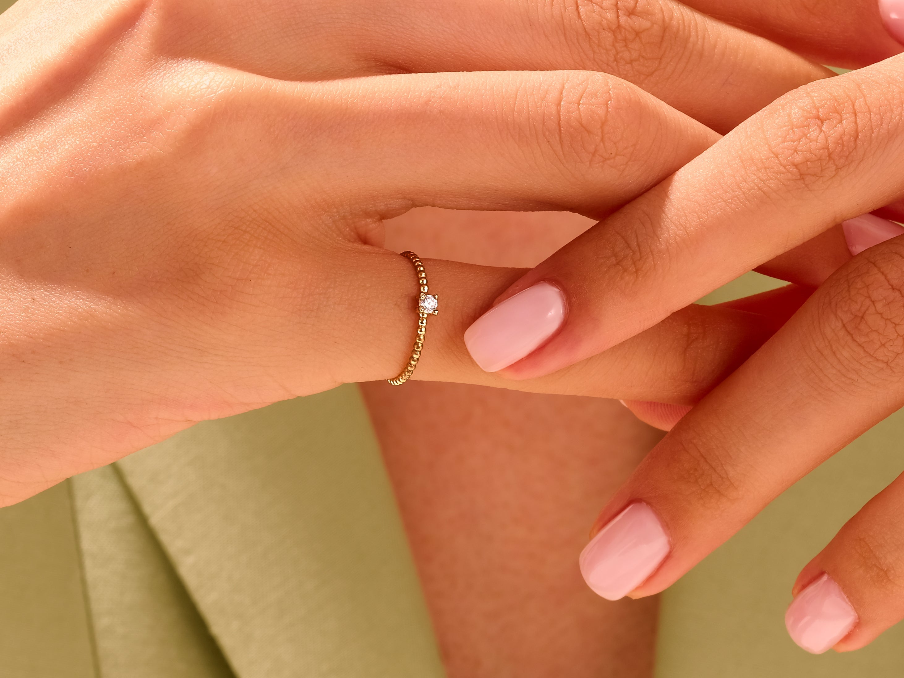 Delicate gold beaded ring with diamond accent on a woman's finger