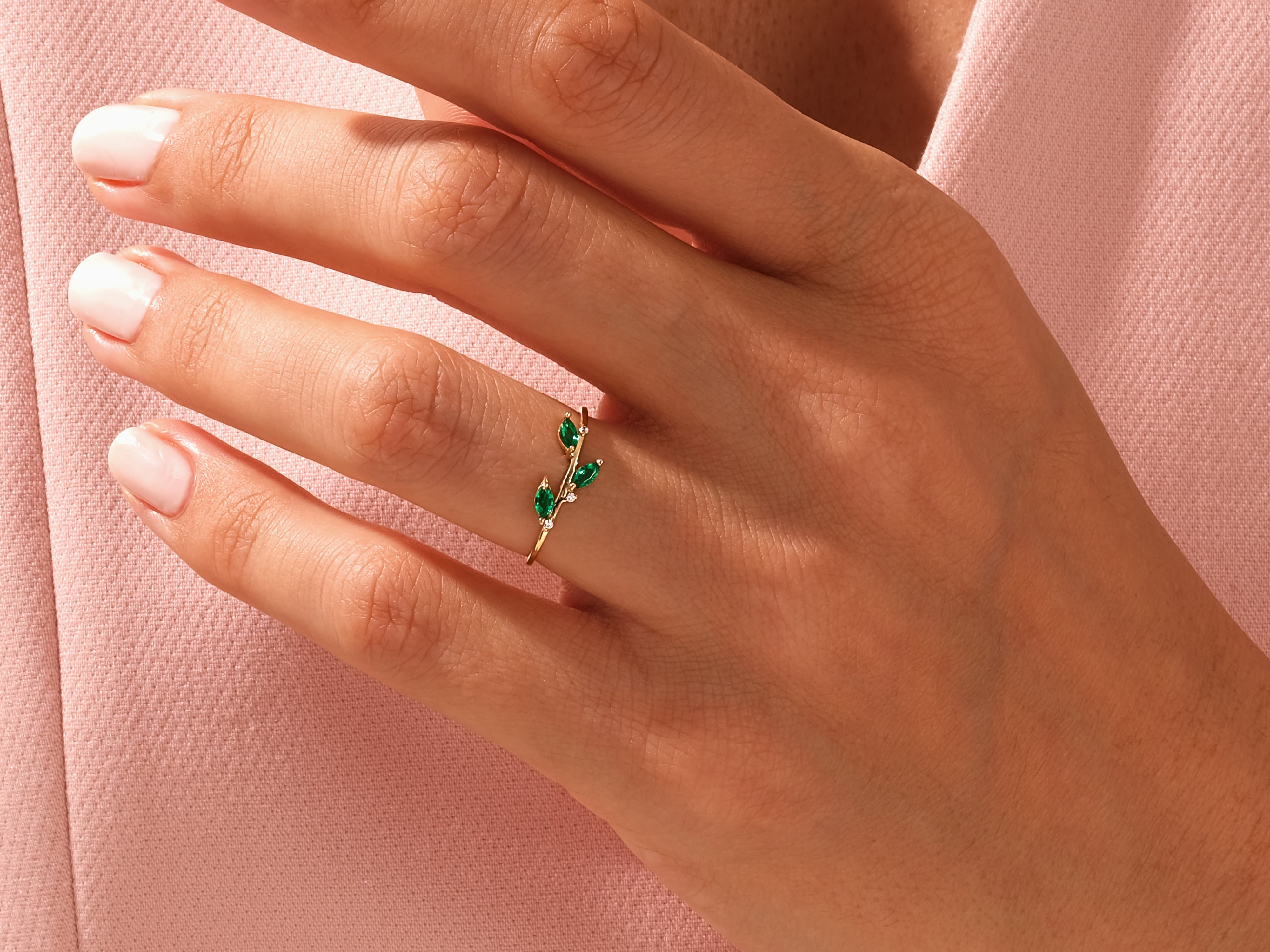 Gold ring with emerald leaves and diamonds on a hand