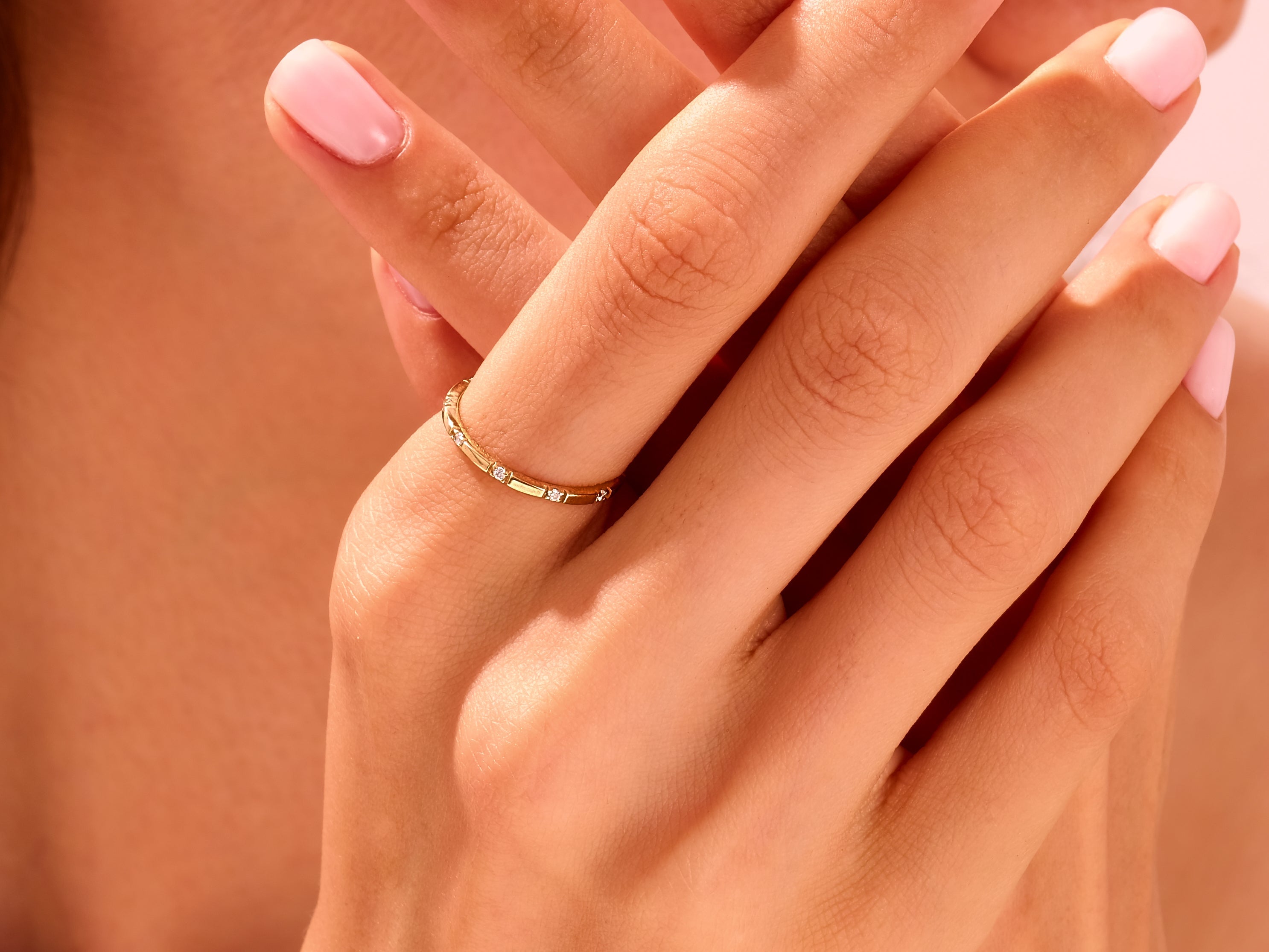 Delicate gold ring with diamonds on a manicured hand