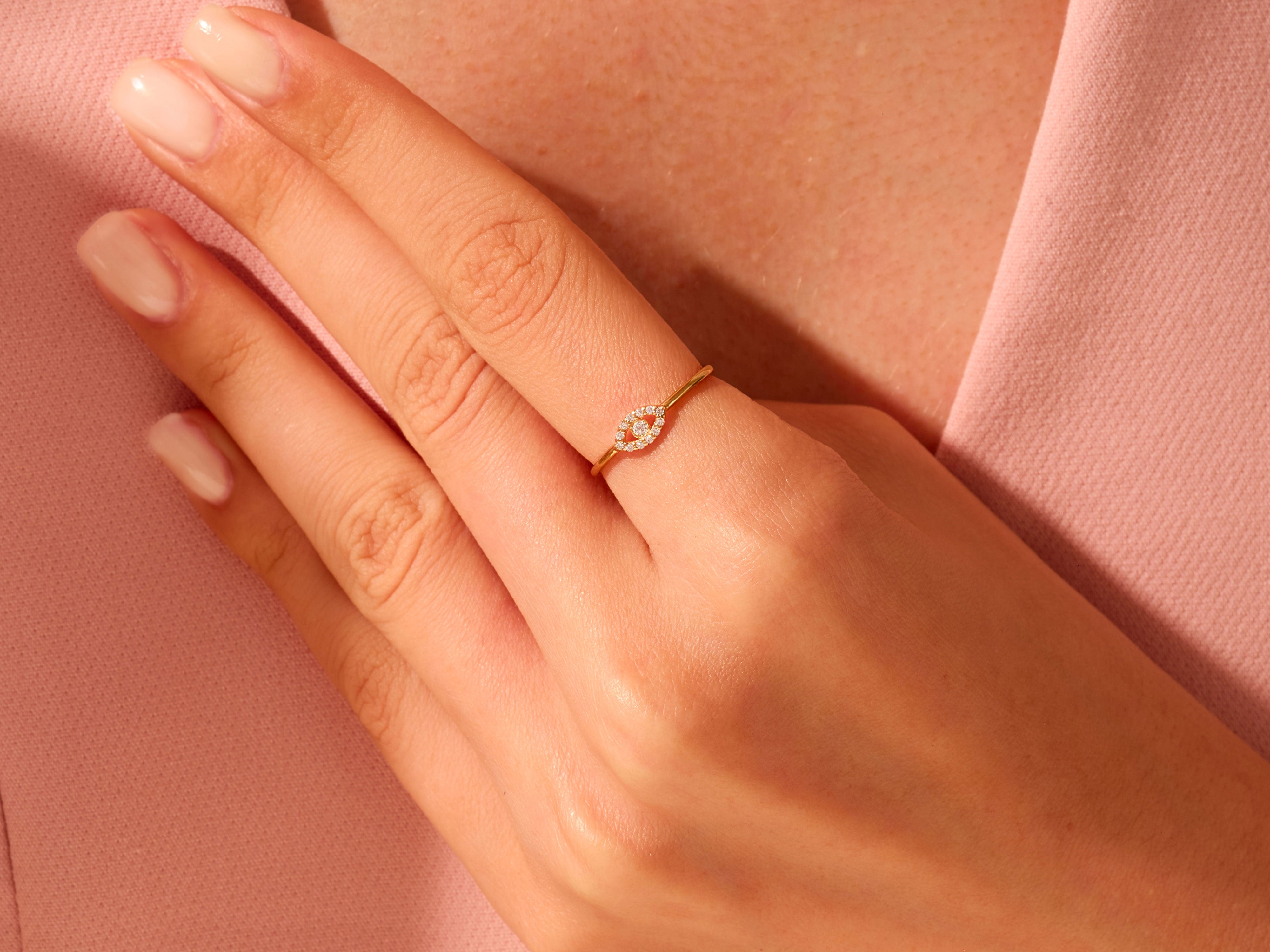 Gold evil eye ring with diamonds on a hand