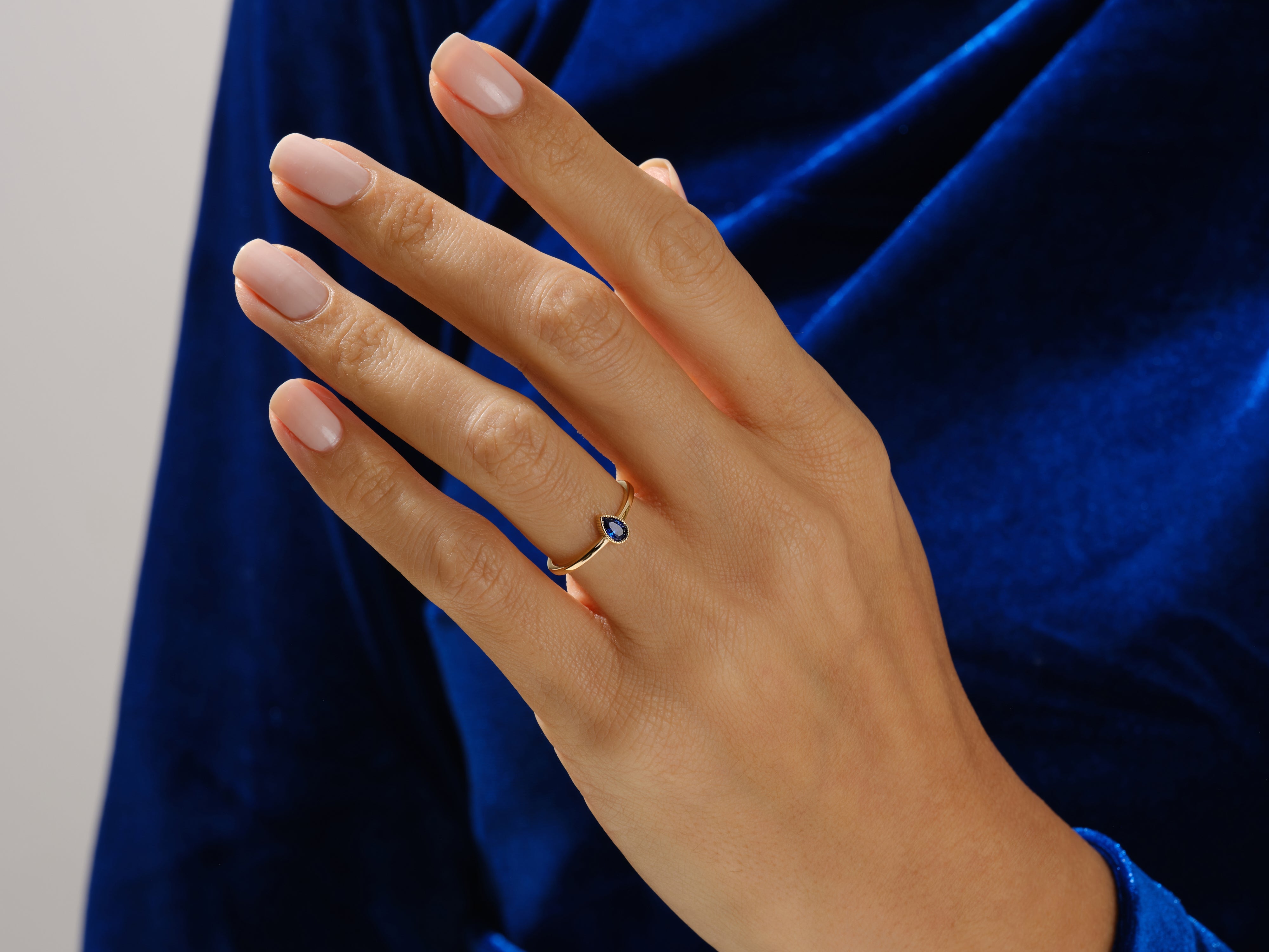 Gold ring with pear-shaped sapphire on hand