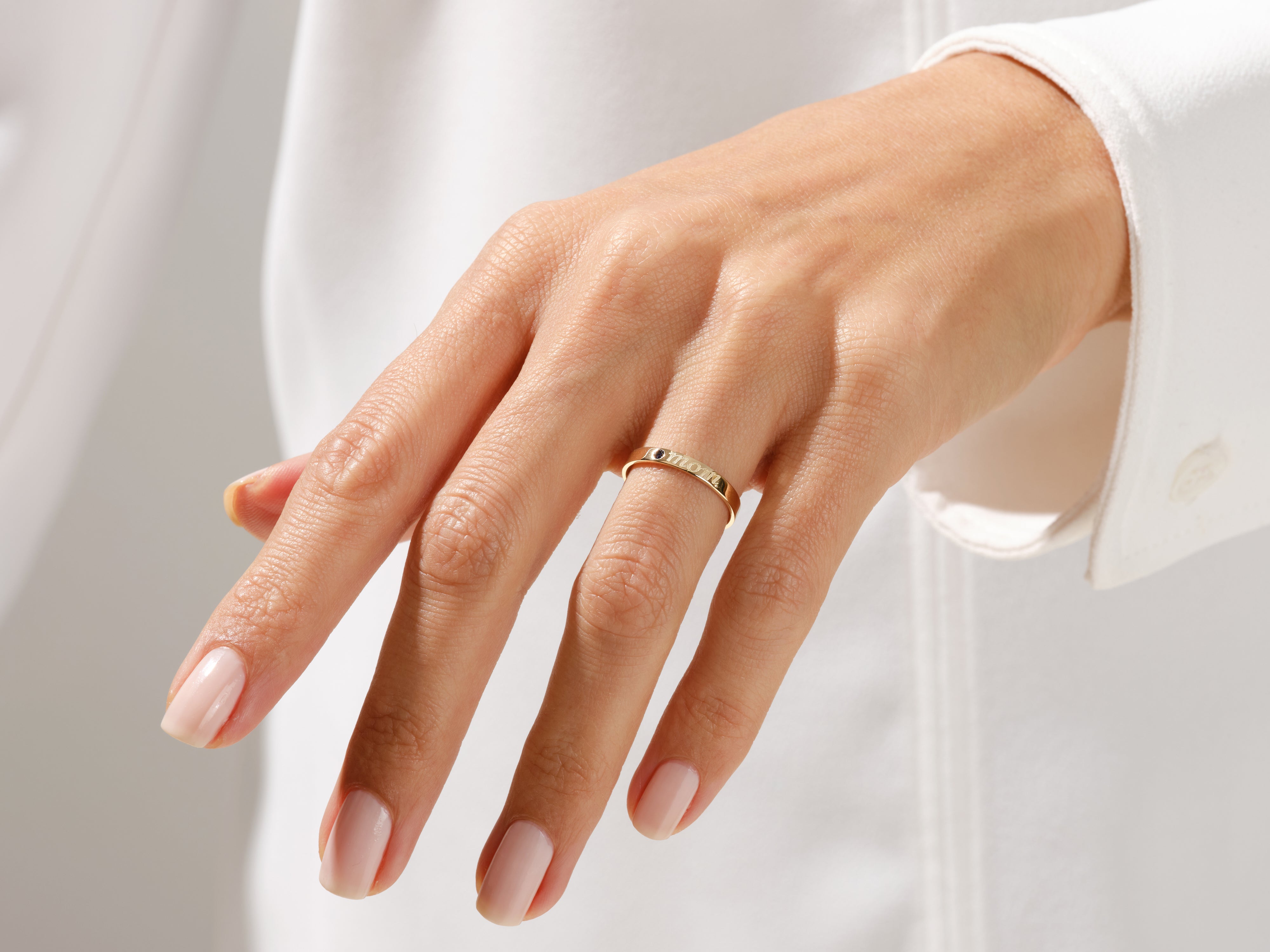 Gold ring with "mom" inscription on a woman's finger