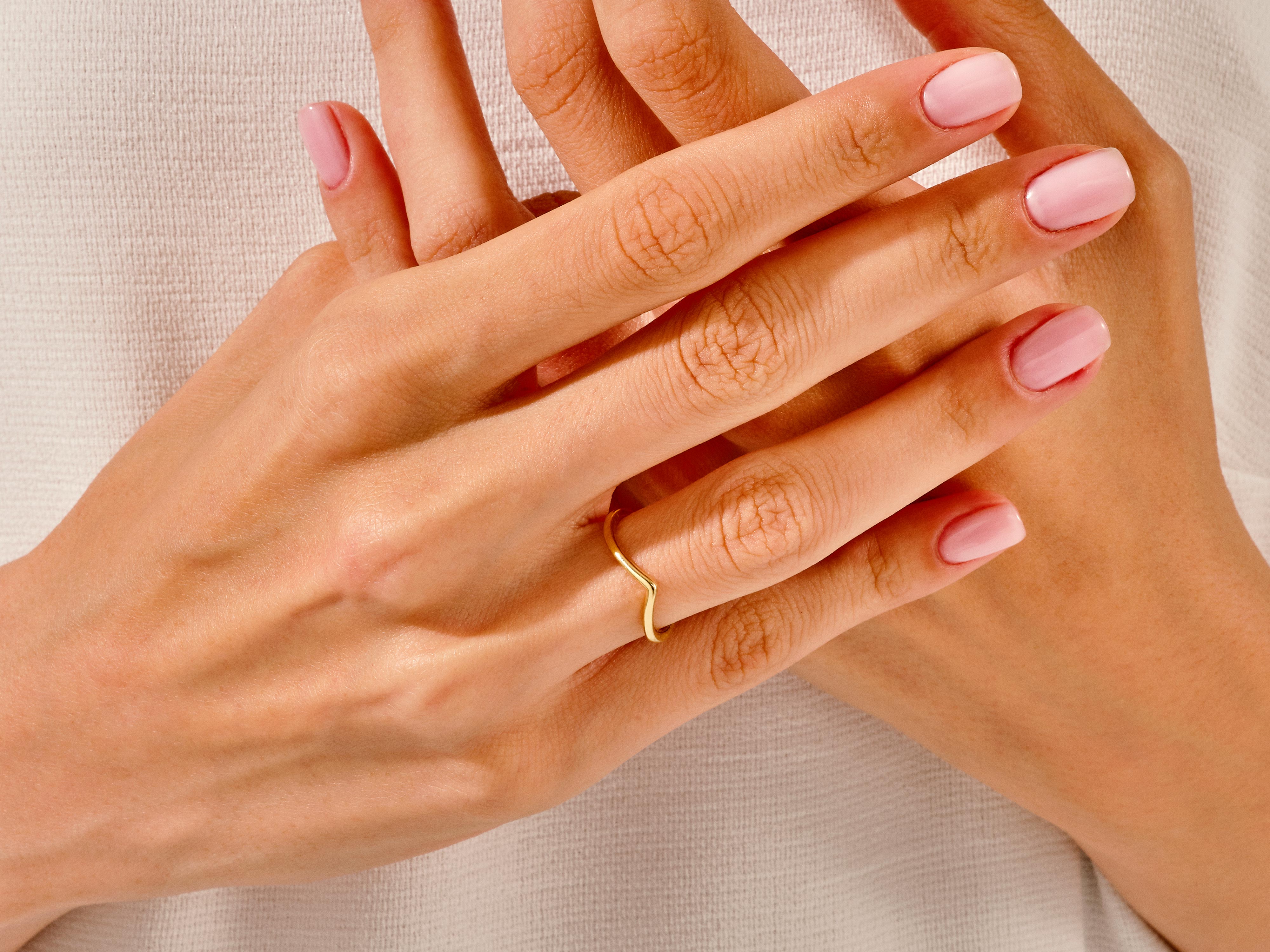 Gold chevron ring on a hand with pink nails