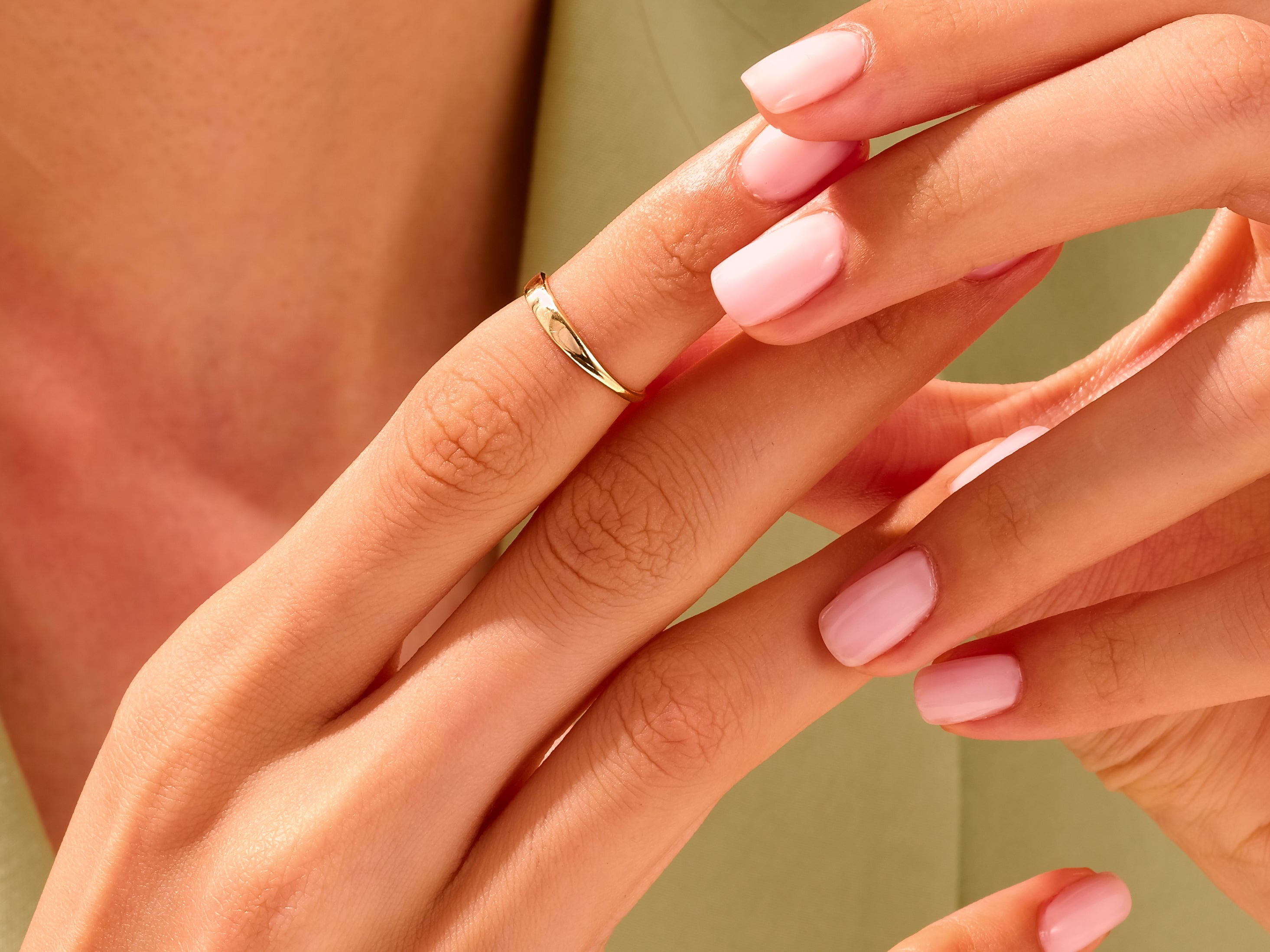 Gold ring on a hand with pink nails, jewelry product