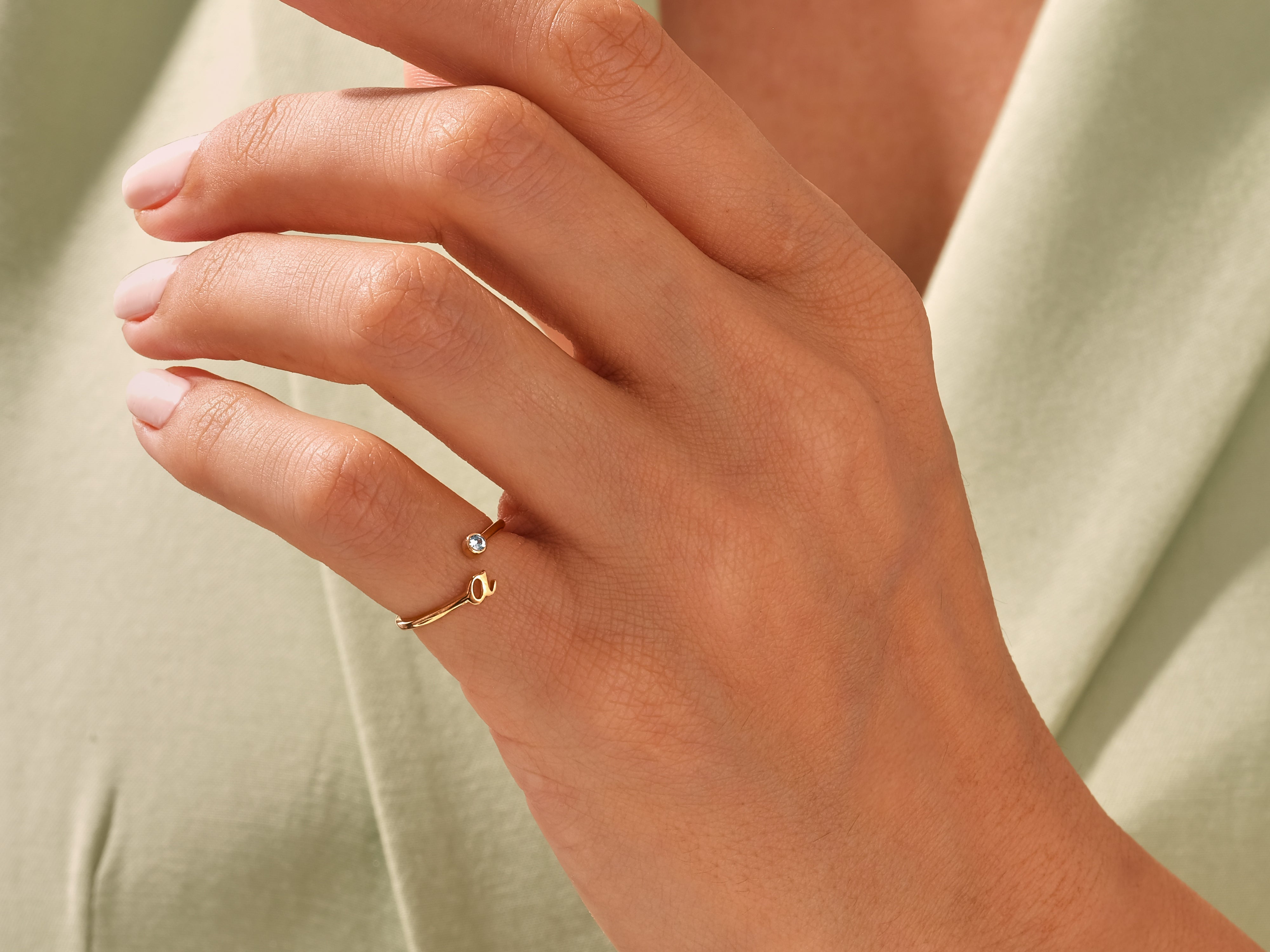 Gold initial ring with diamond accent on hand