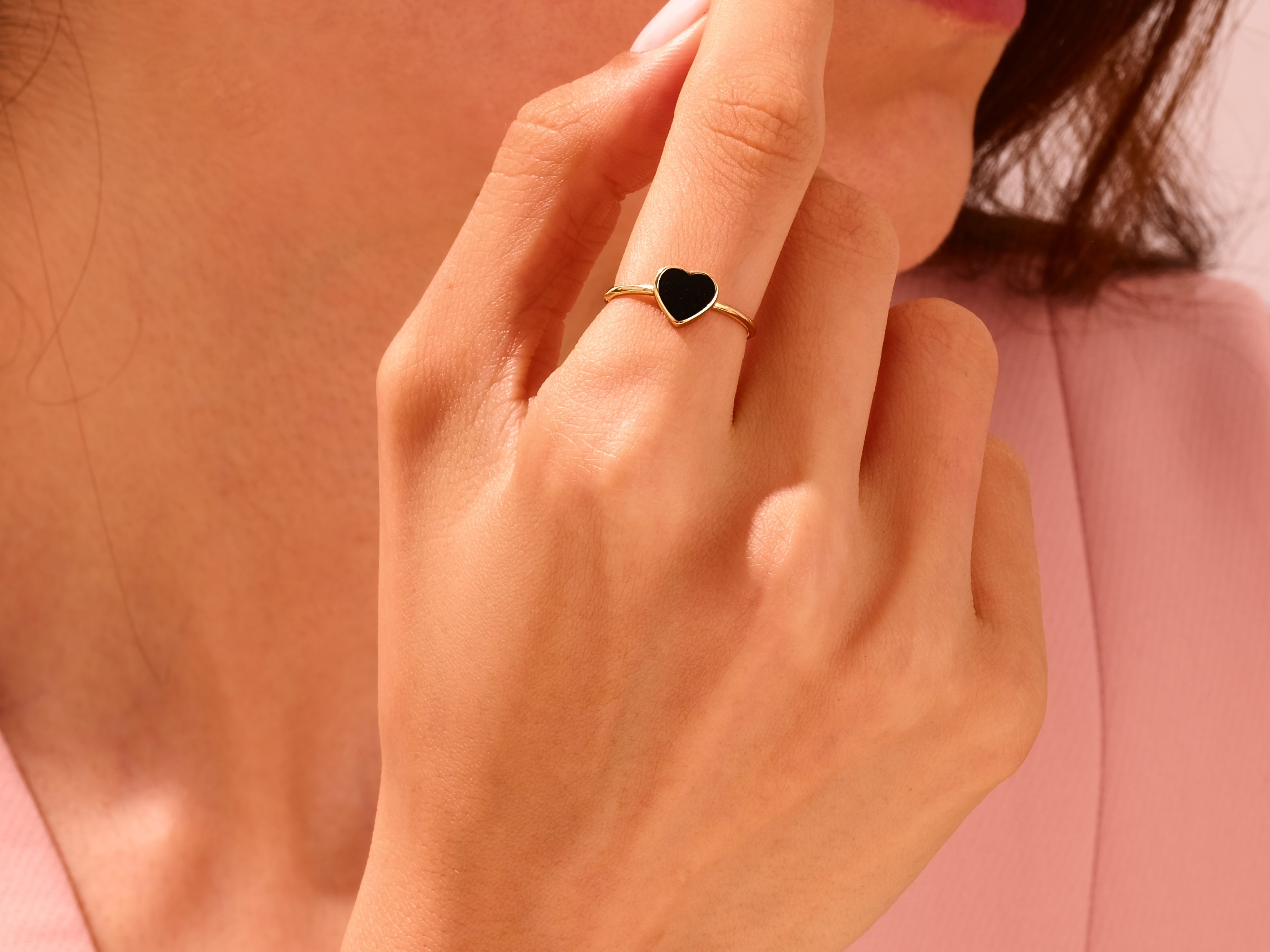 Gold heart ring with black stone on finger