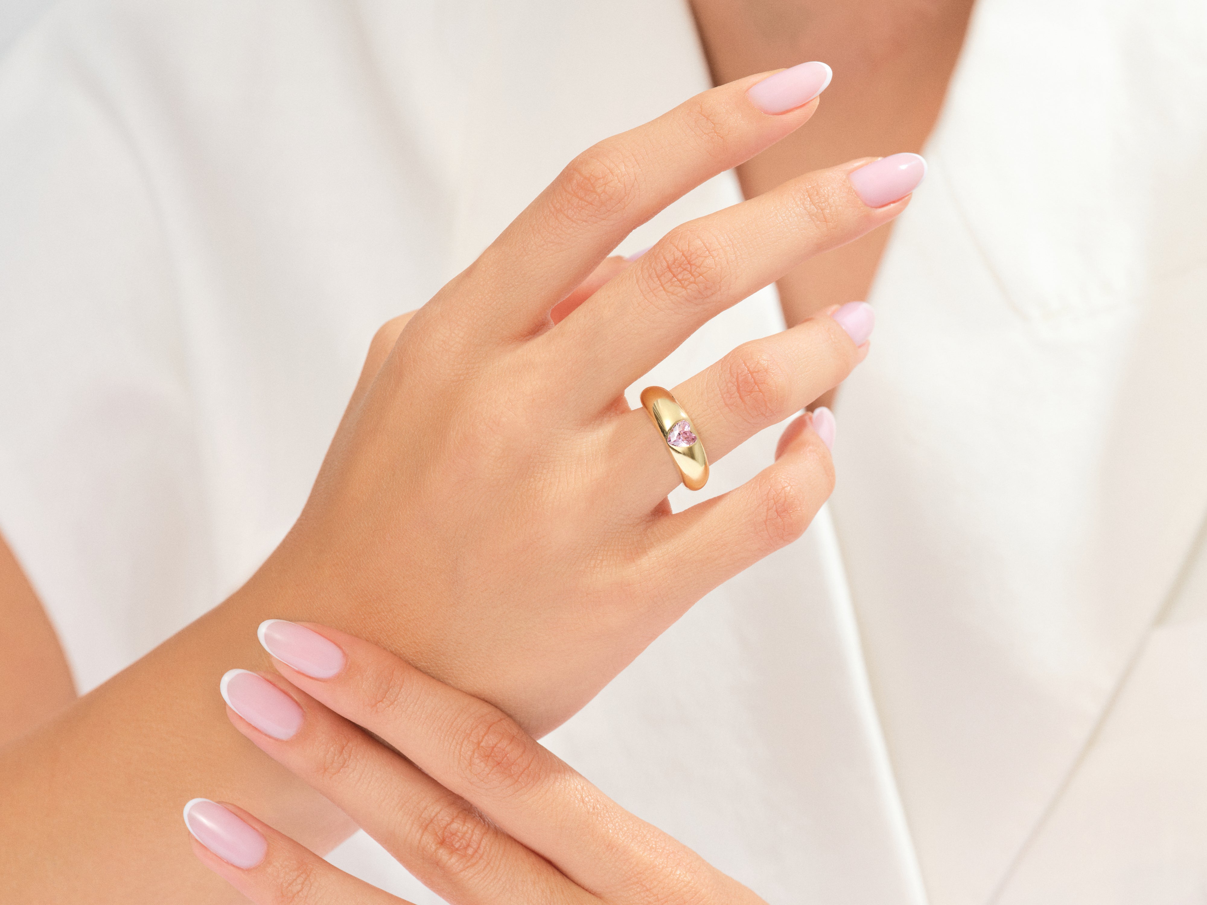 Gold ring with pink heart gemstone on a woman's hand