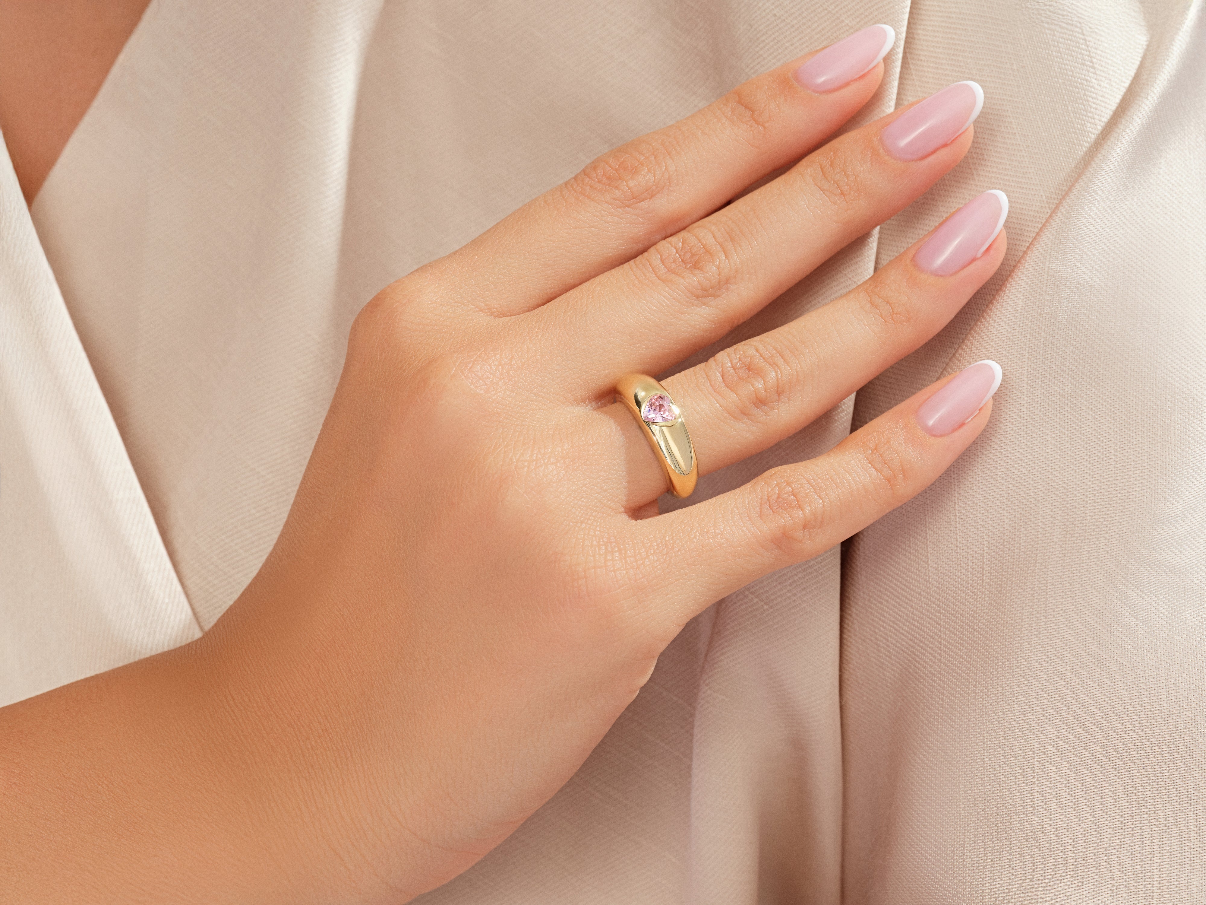 Gold ring with pink heart gem on a woman's hand